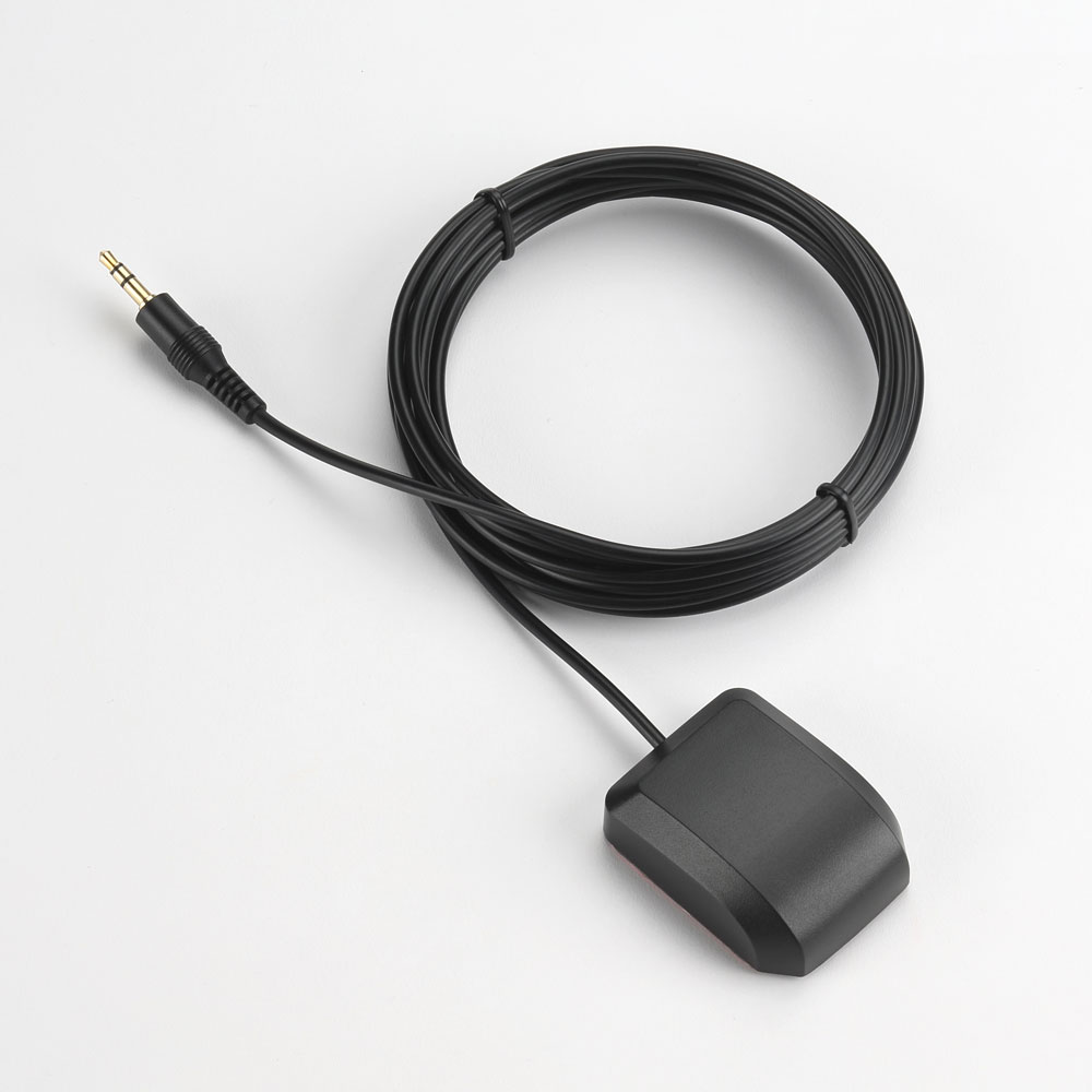 A black cable with a jack, coiled, connected to a black rectangular device with a red adhesive pad, all on a white surface.