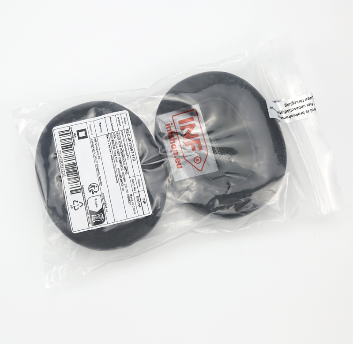 Zwei schwarze Kopfhörerabdeckungen in Plastikverpackung. Etiketten mit Text und Barcode sind sichtbar. Der Hintergrund ist weiß.