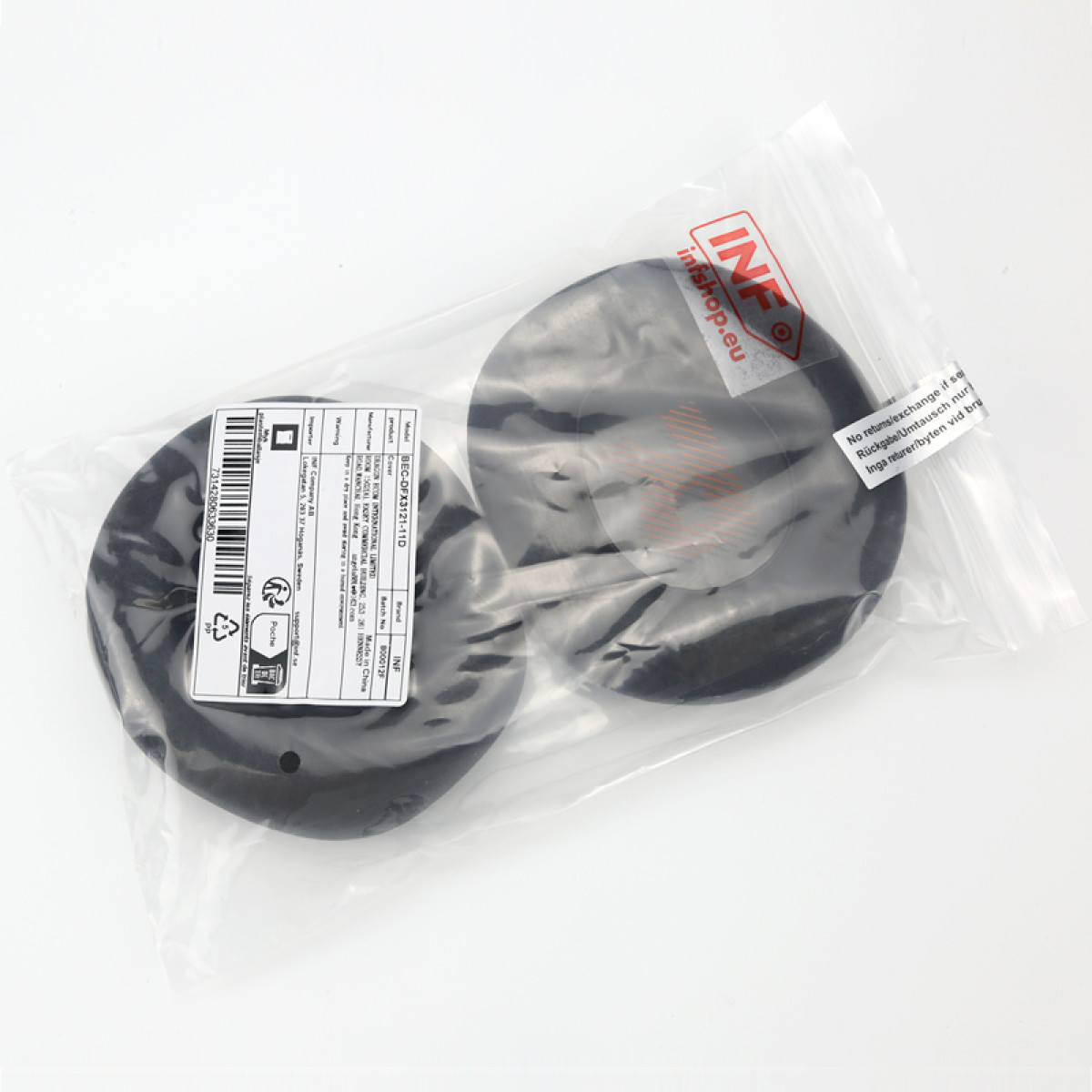 Twee zwarte ronde objecten in een transparante plastic zak, met labels en tekst zichtbaar.