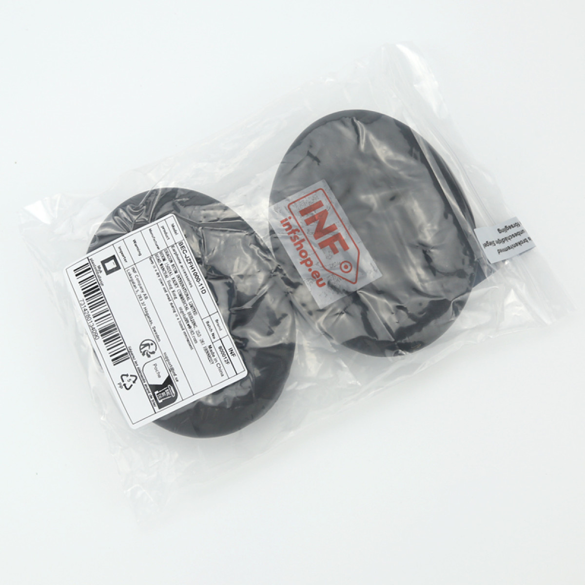 Dwa czarne, okrągłe przedmioty w przezroczystej plastikowej torbie, z widocznymi etykietami. Tło jest białe.