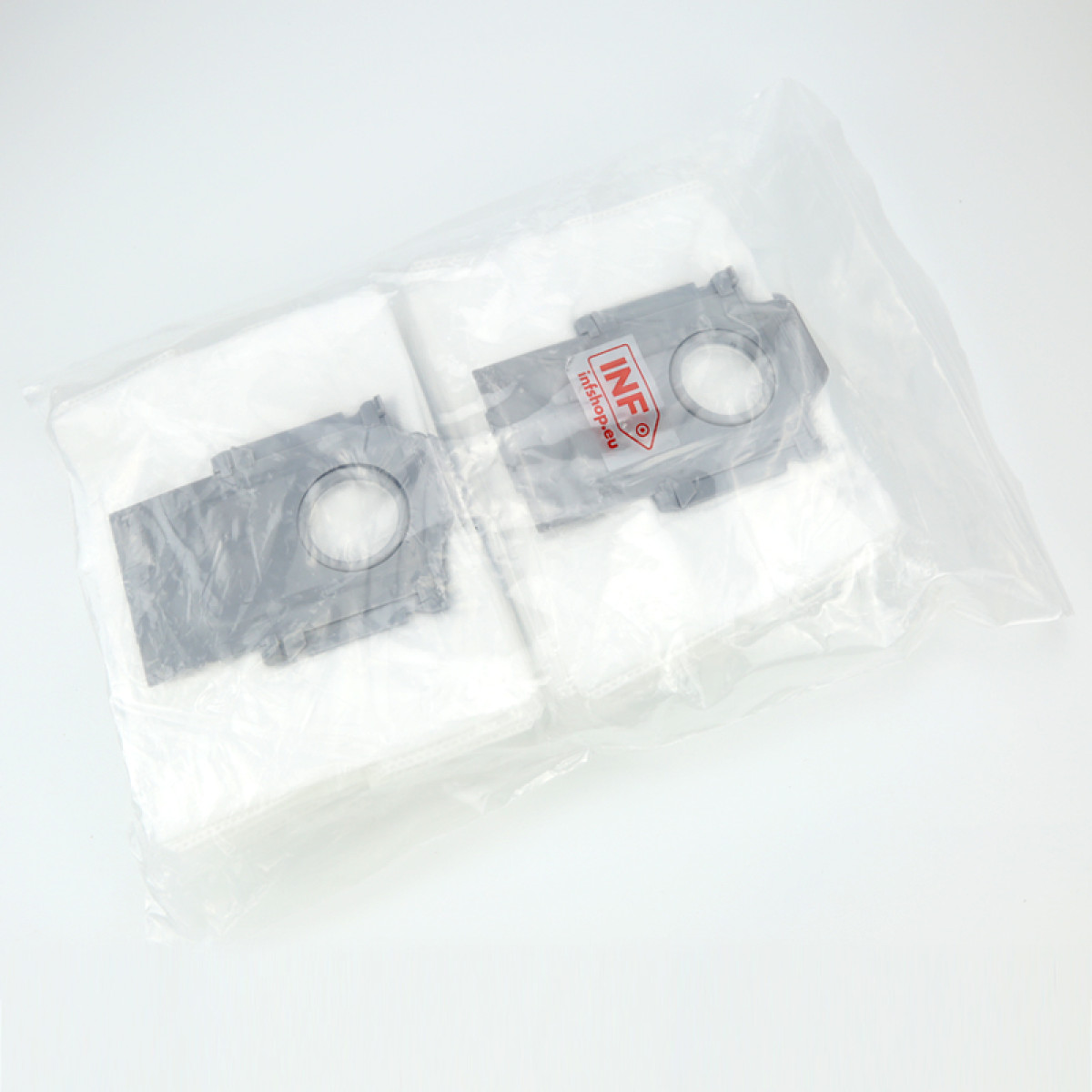 Twee grijze plastic componenten in een doorzichtige plastic zak. De componenten hebben cirkelvormige gaten en liggen op witte stof.