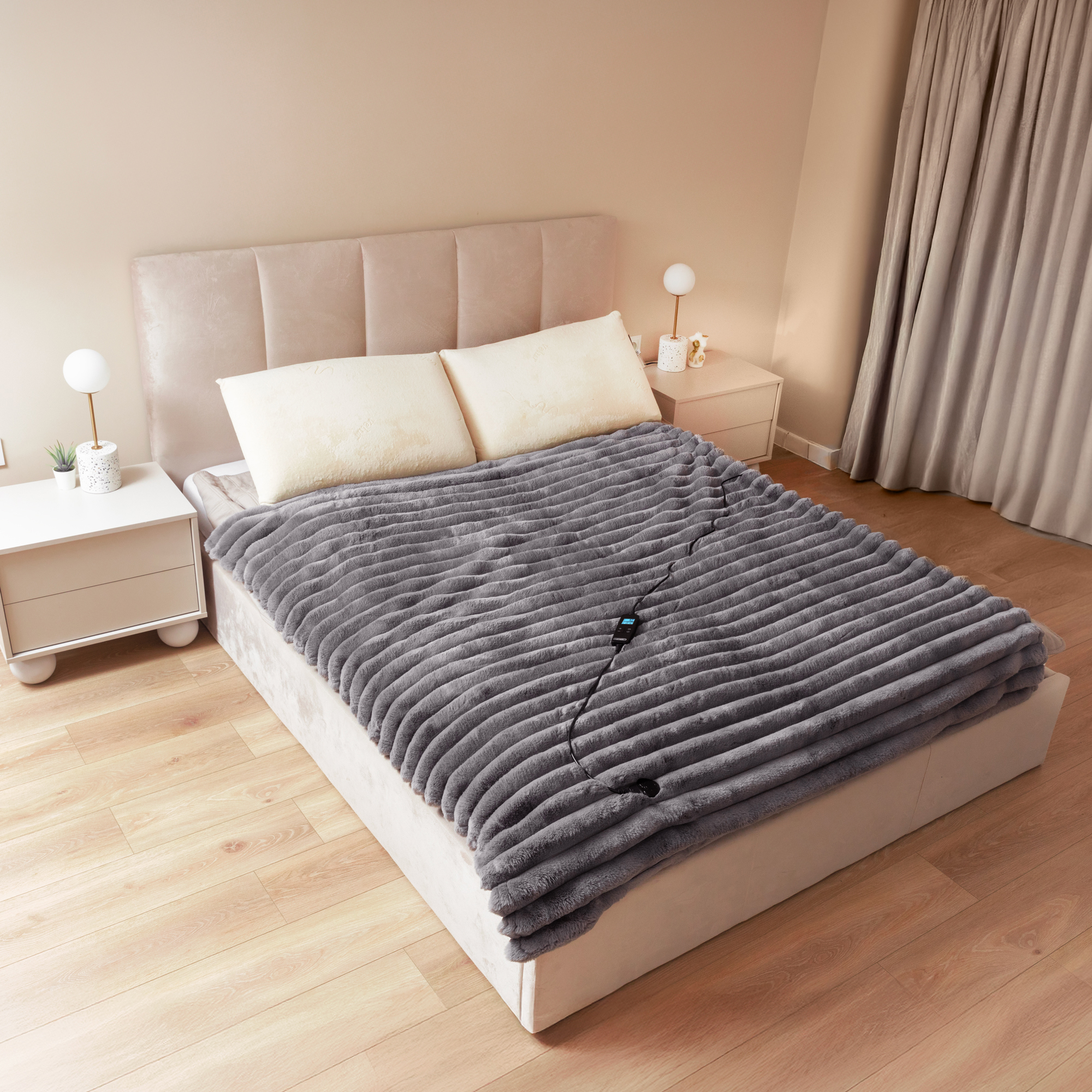 Sypialnia z szarą kołdrą, białymi poduszkami i dwoma szafkami nocnymi. Podłoga drewniana.