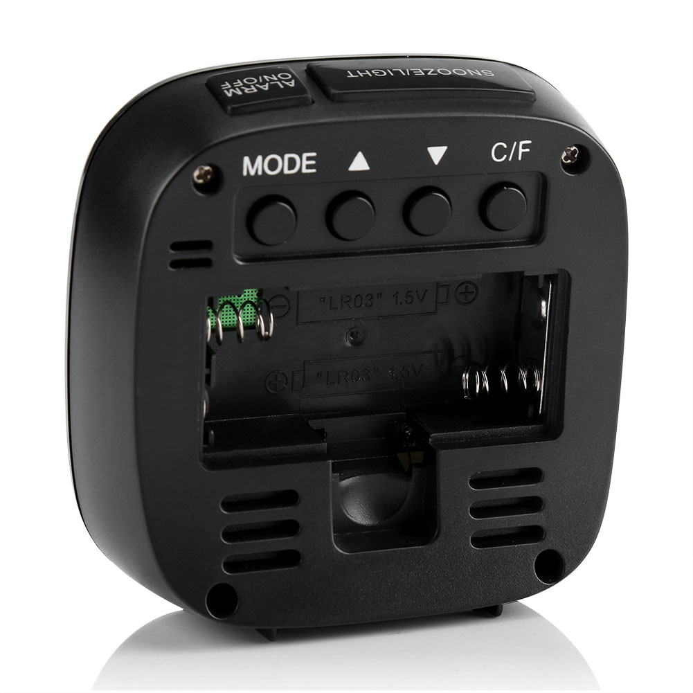 Schwarzer Digitalwecker mit Knöpfen und offenem Batteriefach. Zu den Knöpfen gehören MODE, Alarm, Schlummerfunktion und C/F. Batterieinfo ist sichtbar.