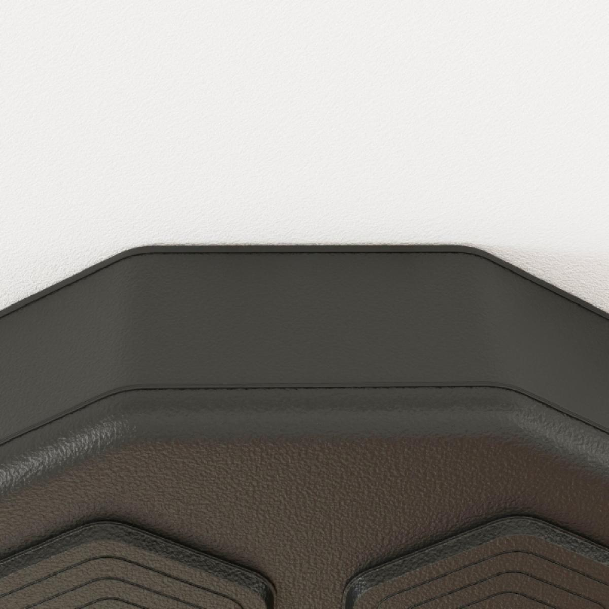 Nahaufnahme einer dunkelgrauen Gummi-Automatte vor einer weißen Wand. Die Matte hat eine strukturierte Oberfläche mit gemusterten Details.