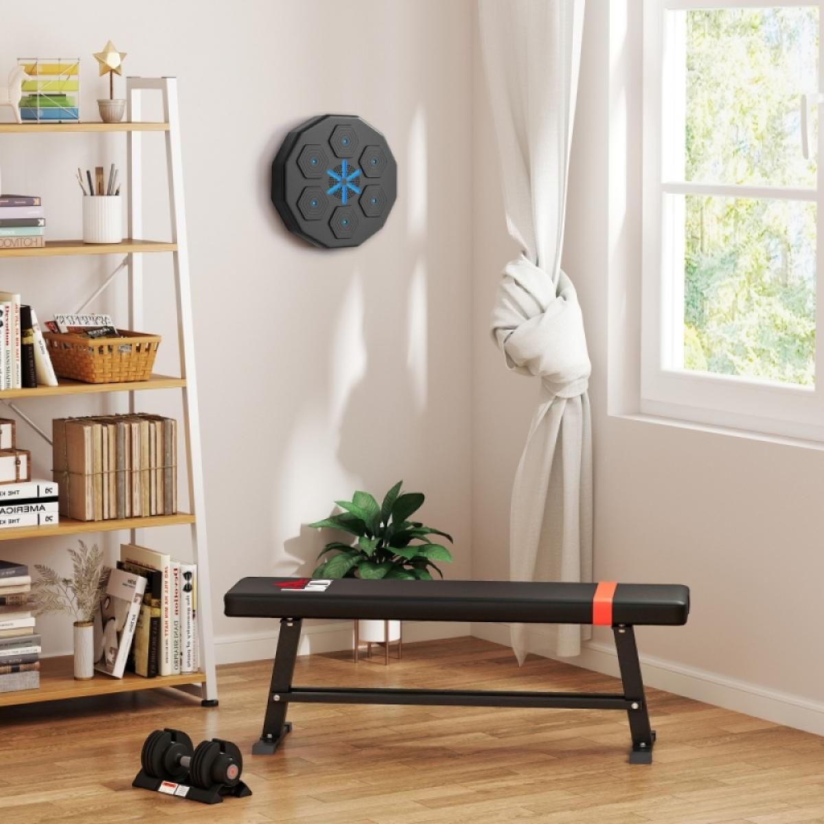 Zimmer mit Fitnessgeräten. Bank, Hanteln und ein Wandgerät. Regale mit Büchern und Pflanzen. Fenster mit Vorhängen.