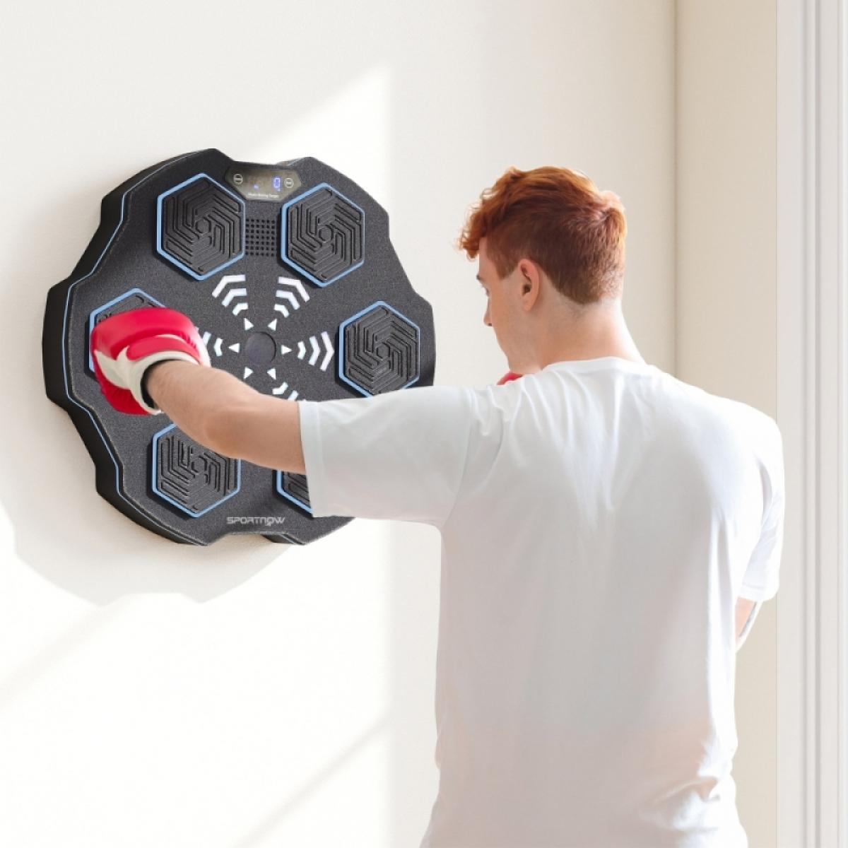 Ein Mann mit roten Haaren boxt auf ein Wand-Boxziel. Er trägt ein weißes Hemd und rote Boxhandschuhe. Das Ziel hat blaue Akzente.