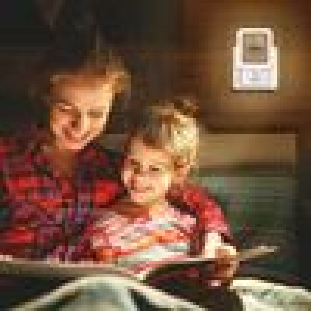 Eine Frau und ein Kind lesen gemeinsam im Bett ein Buch. Eine Nachttischlampe befindet sich an der Wand.