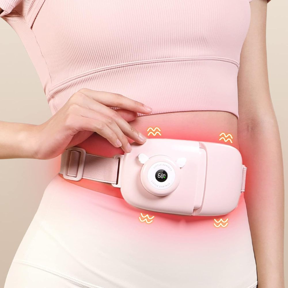 Eine Person trägt ein rosa Heizkissen um die Taille. Das Kissen hat eine Digitalanzeige mit 68 Grad. Rosa Wellenlinien zeigen Wärme an.