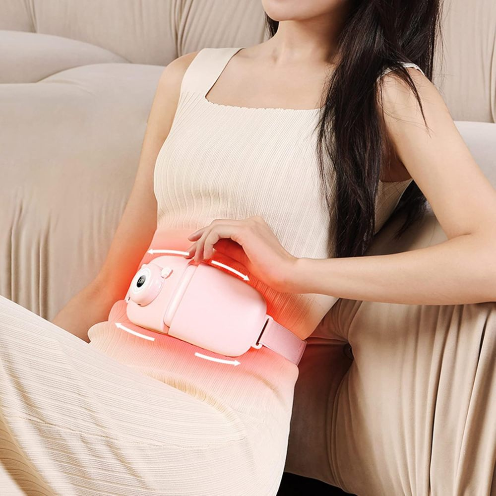 Eine Frau sitzt mit einem rosa Therapiegerät auf dem Bauch. Das Gerät ist um ihre Taille geschnallt. Rotes Licht geht vom Gerät aus.