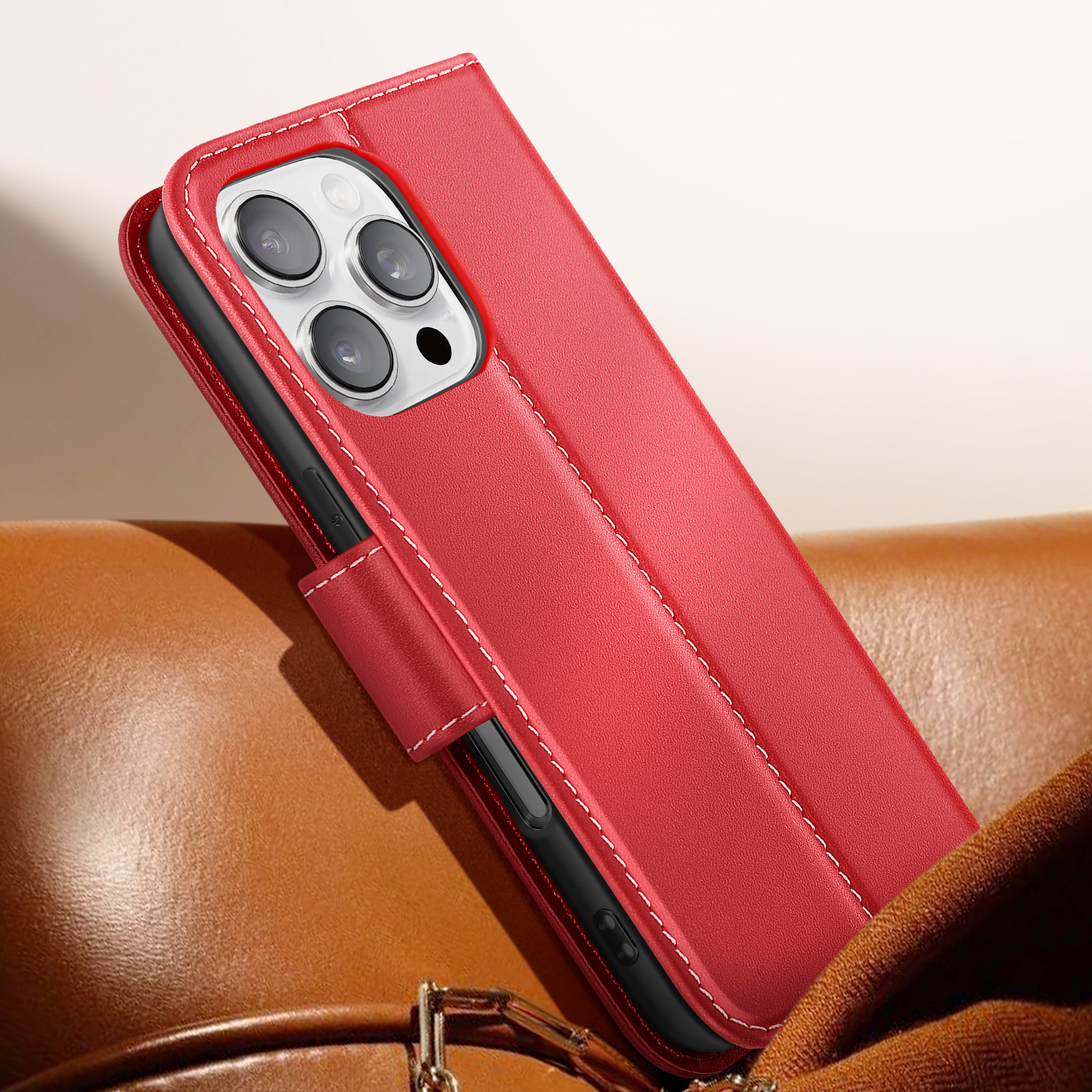 Custodia rossa per telefono con cuciture bianche, aperta. Mostra le fotocamere del telefono. Su superficie in pelle marrone con tessuto marrone.