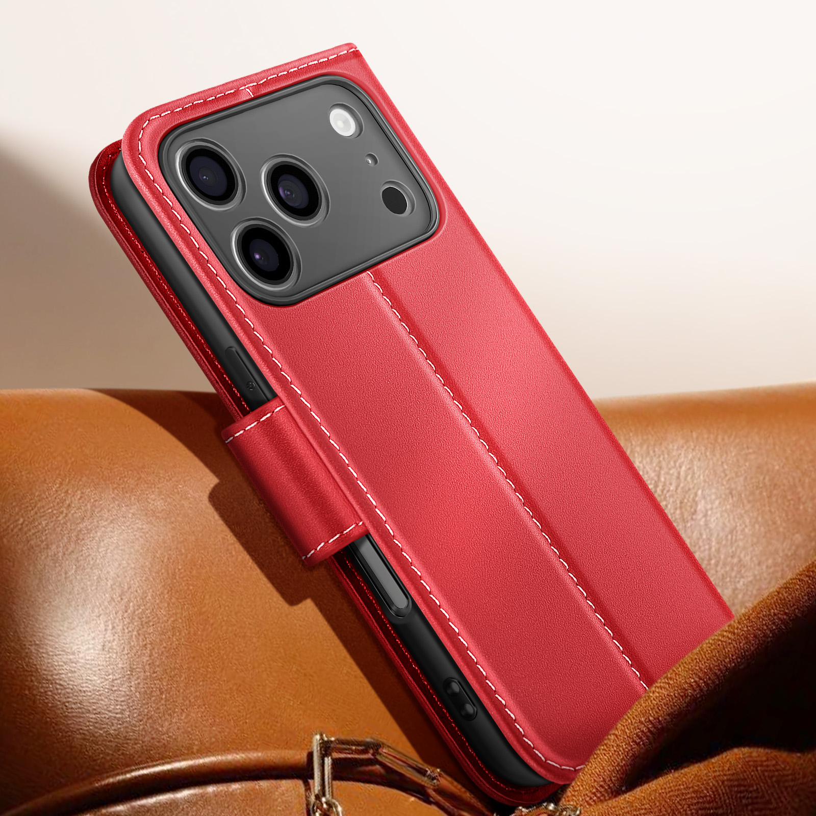Custodia per telefono in pelle rossa, cuciture bianche, su superficie in pelle marrone. Il telefono ha più fotocamere.