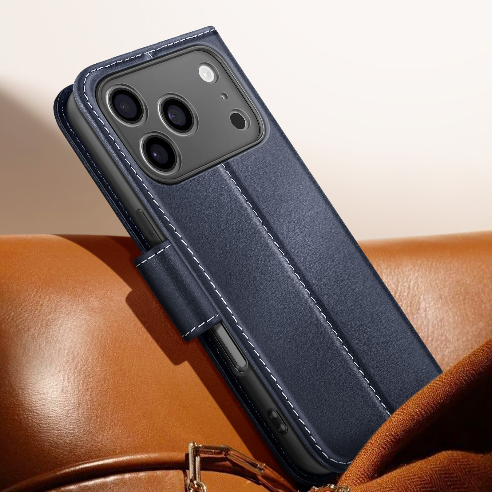 Una custodia blu navy con cuciture bianche è su una superficie di pelle marrone. Il telefono ha tre fotocamere.