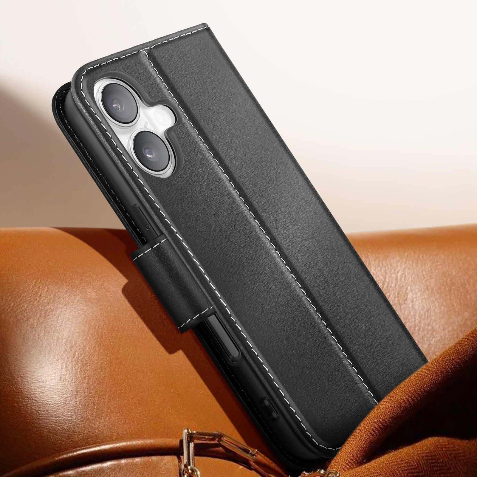 Custodia per telefono in pelle nera con cuciture bianche, aperta. È su una superficie in pelle marrone. Fotocamera del telefono visibile.