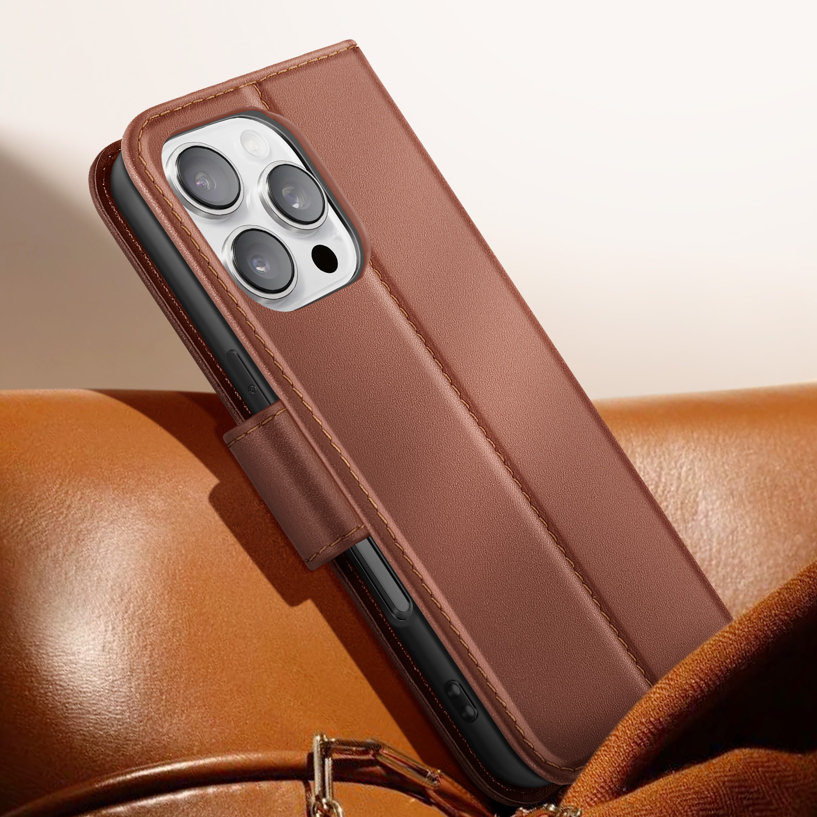 Custodia per telefono in pelle marrone con telefono. Quattro obiettivi visibili. La custodia è su pelle marrone.