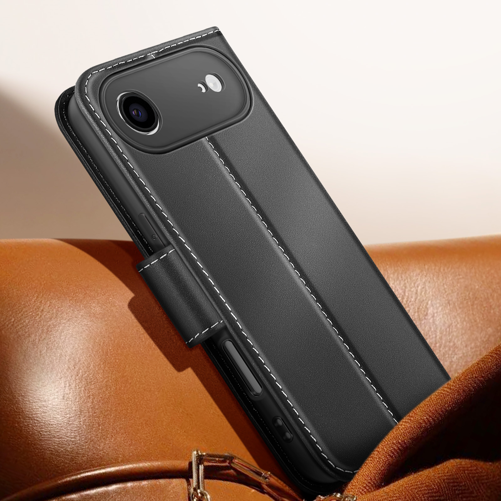 Custodia per telefono in pelle nera con cuciture bianche, su una superficie in pelle marrone. La custodia è aperta, mostrando la fotocamera del telefono.