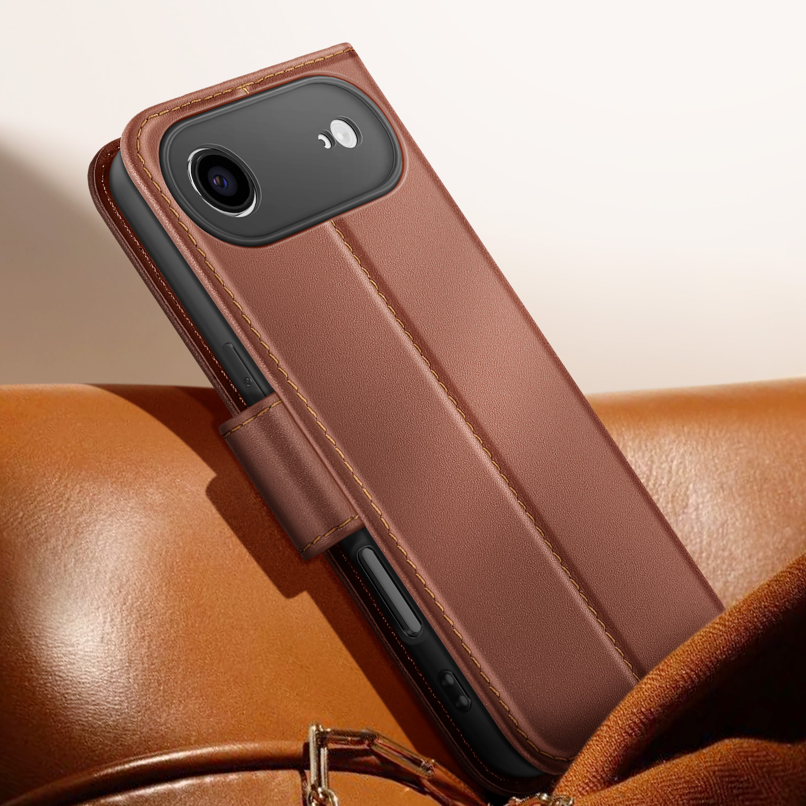 Custodia per telefono in pelle marrone con cuciture, aperta, che rivela la fotocamera del telefono. Appoggiata sul cuoio.