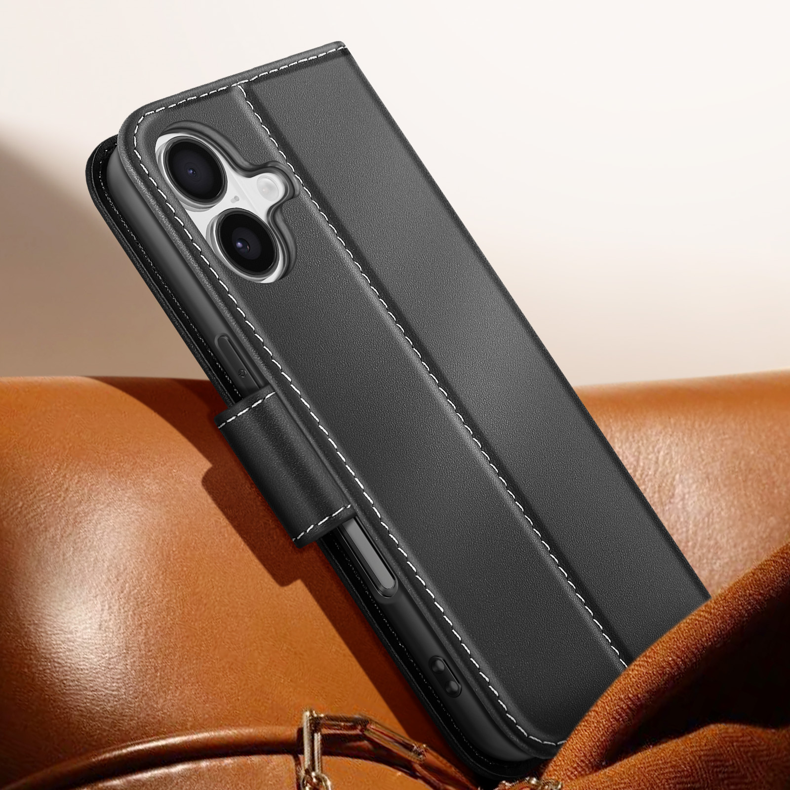 Custodia per telefono nera con cuciture bianche, aperta. È su una superficie di pelle marrone, con una borsa marrone sullo sfondo.