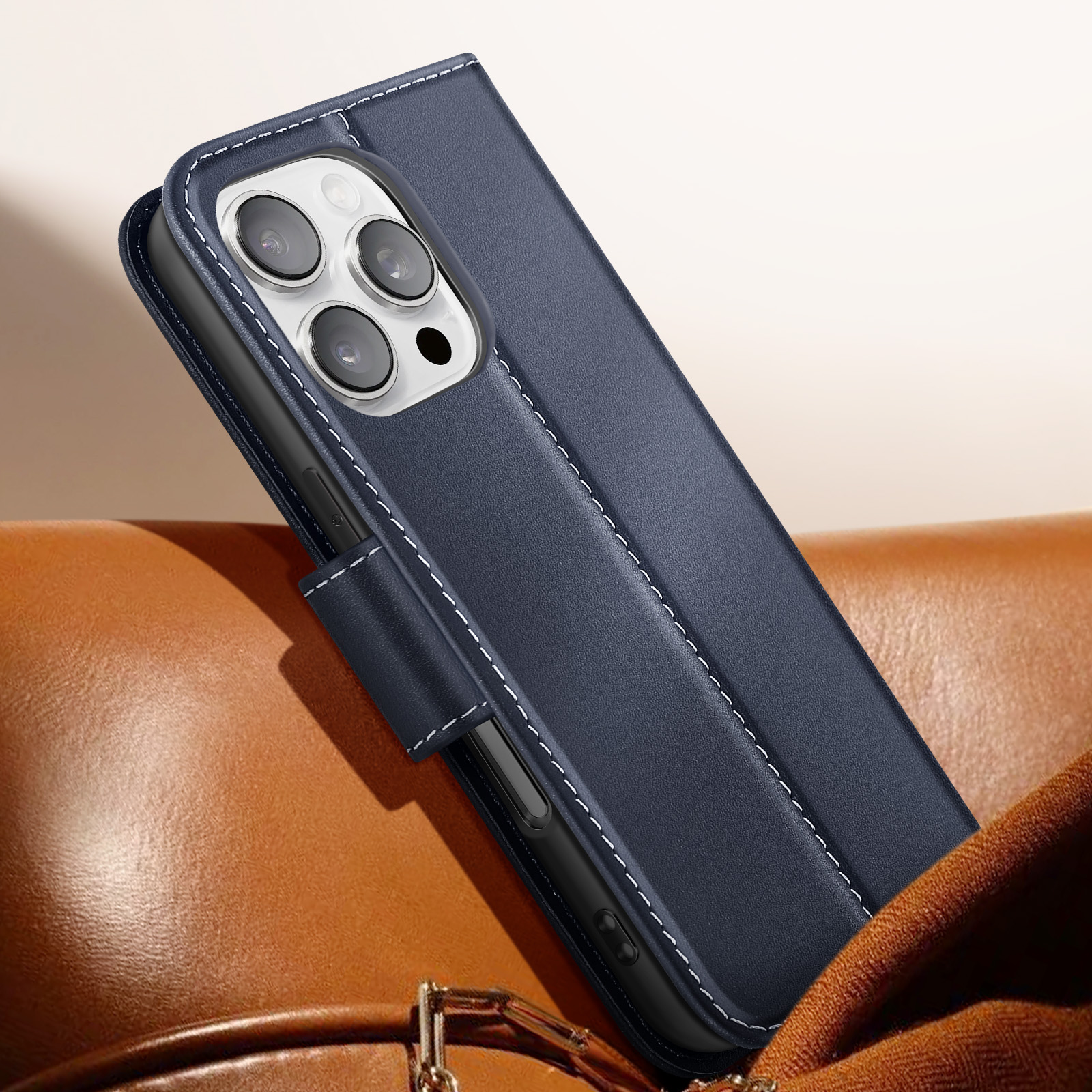 Custodia per telefono blu scuro su superficie in pelle marrone. Fotocamere del telefono visibili e dettagli di cuciture bianche.