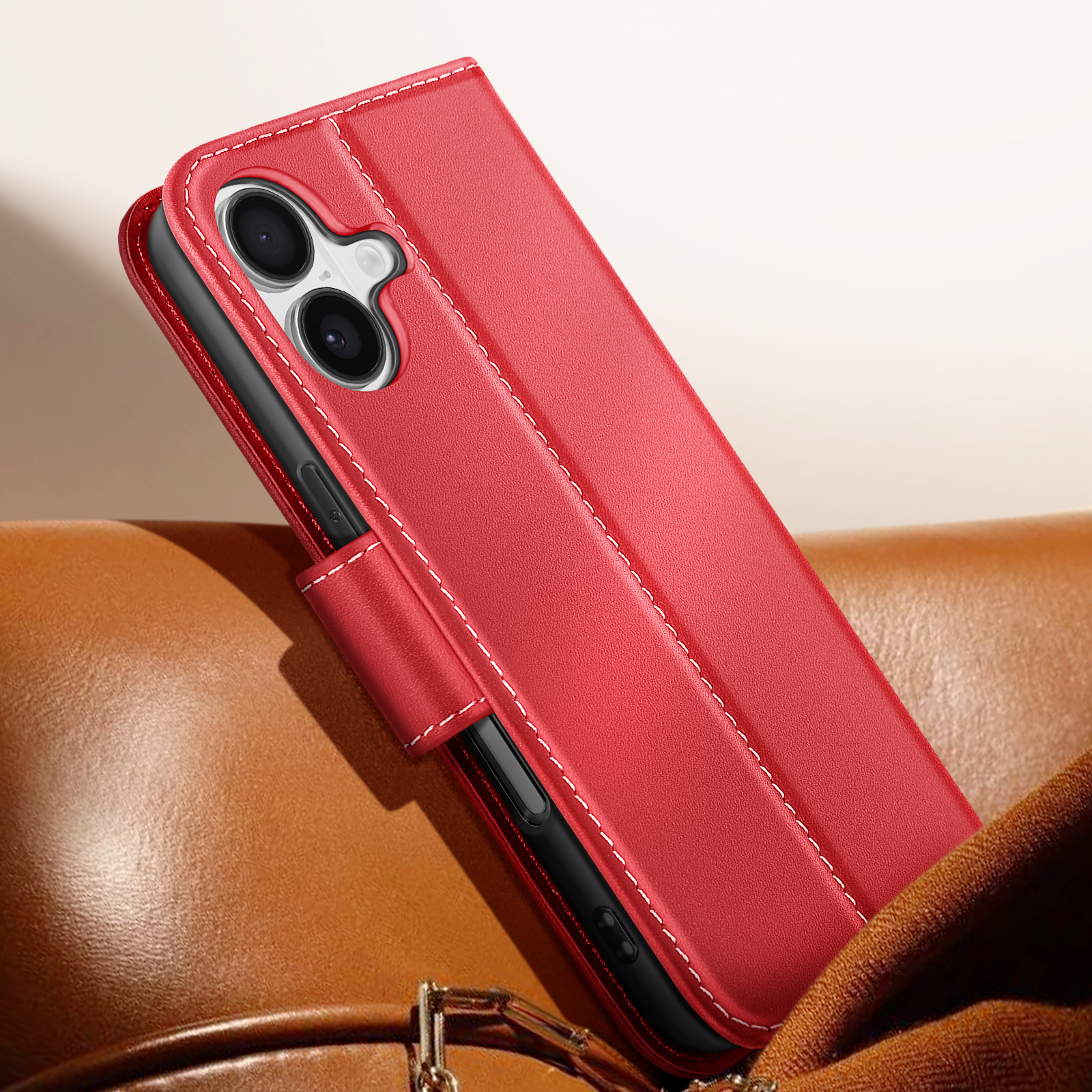 Custodia per telefono rossa, cuciture bianche, texture in pelle, telefono nero all'interno. Tenuta su pelle marrone e tessuto marrone.