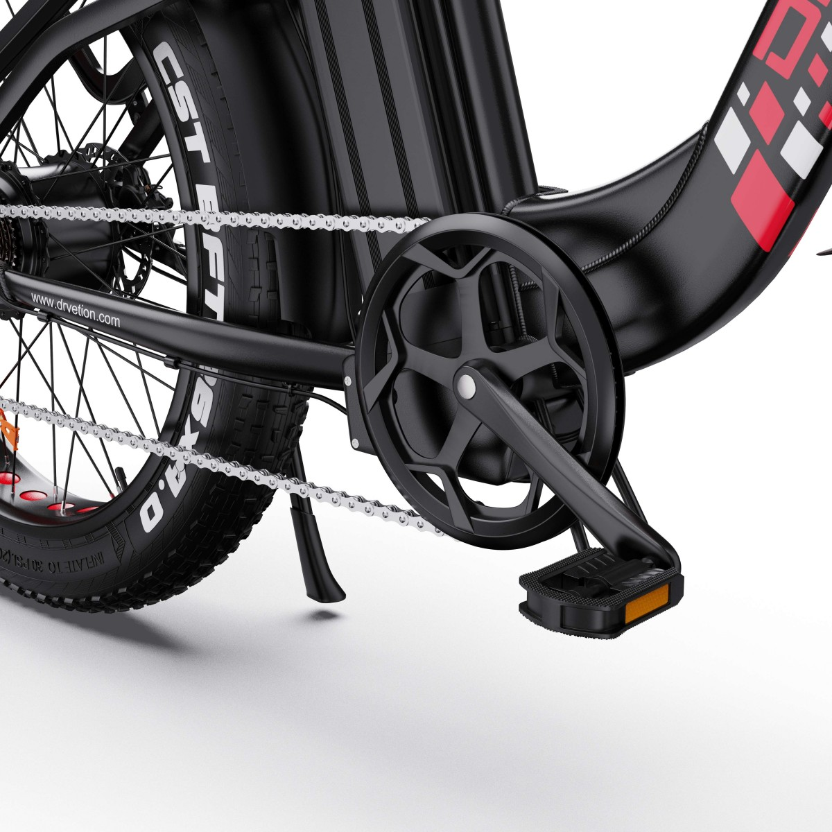 Zbliżenie czarnego roweru elektrycznego. Widoczny jest łańcuch, pedał, opona i rama. Rower stoi na białej powierzchni.