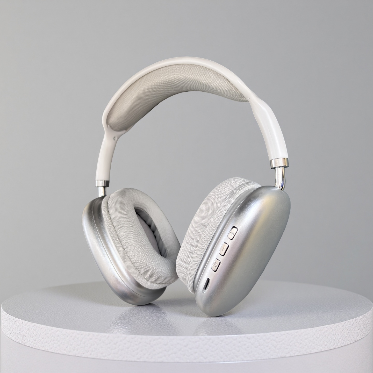 Auriculares plateados sobre una superficie blanca, contra un fondo gris. Los auriculares tienen almohadillas grises y una diadema blanca.