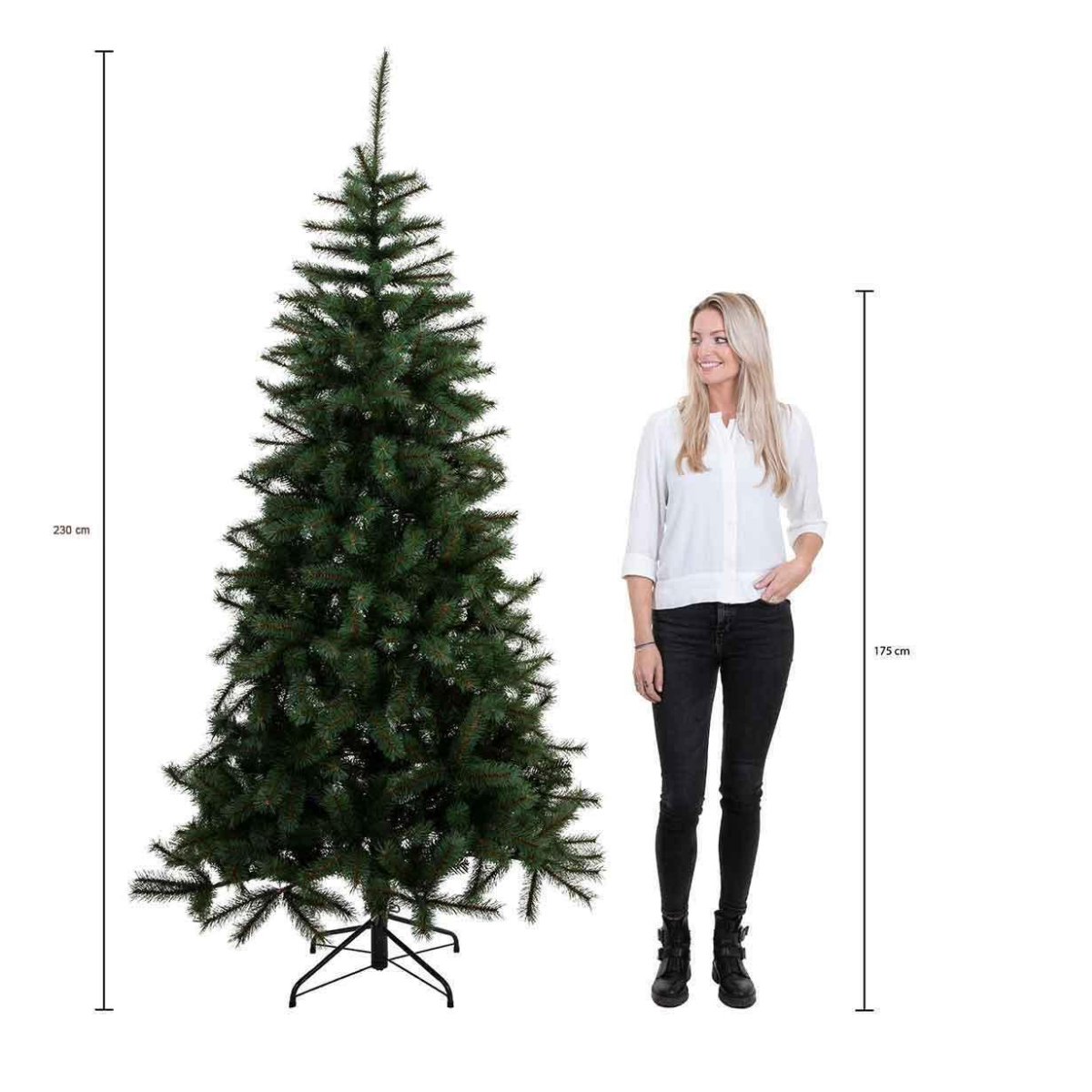 Un sapin de Noël vert à côté d'une femme. L'arbre mesure 230 cm, la femme 175 cm. La femme porte une chemise blanche et un pantalon noir.