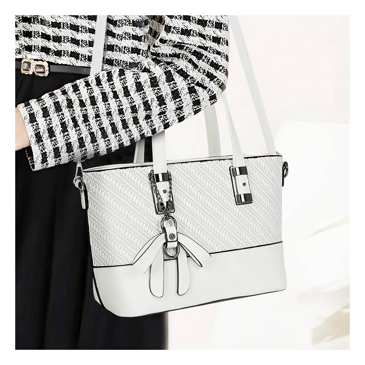 Una mujer sostiene un bolso blanco. Lleva una chaqueta a cuadros en blanco y negro. El bolso tiene textura tejida y detalles de cuero.