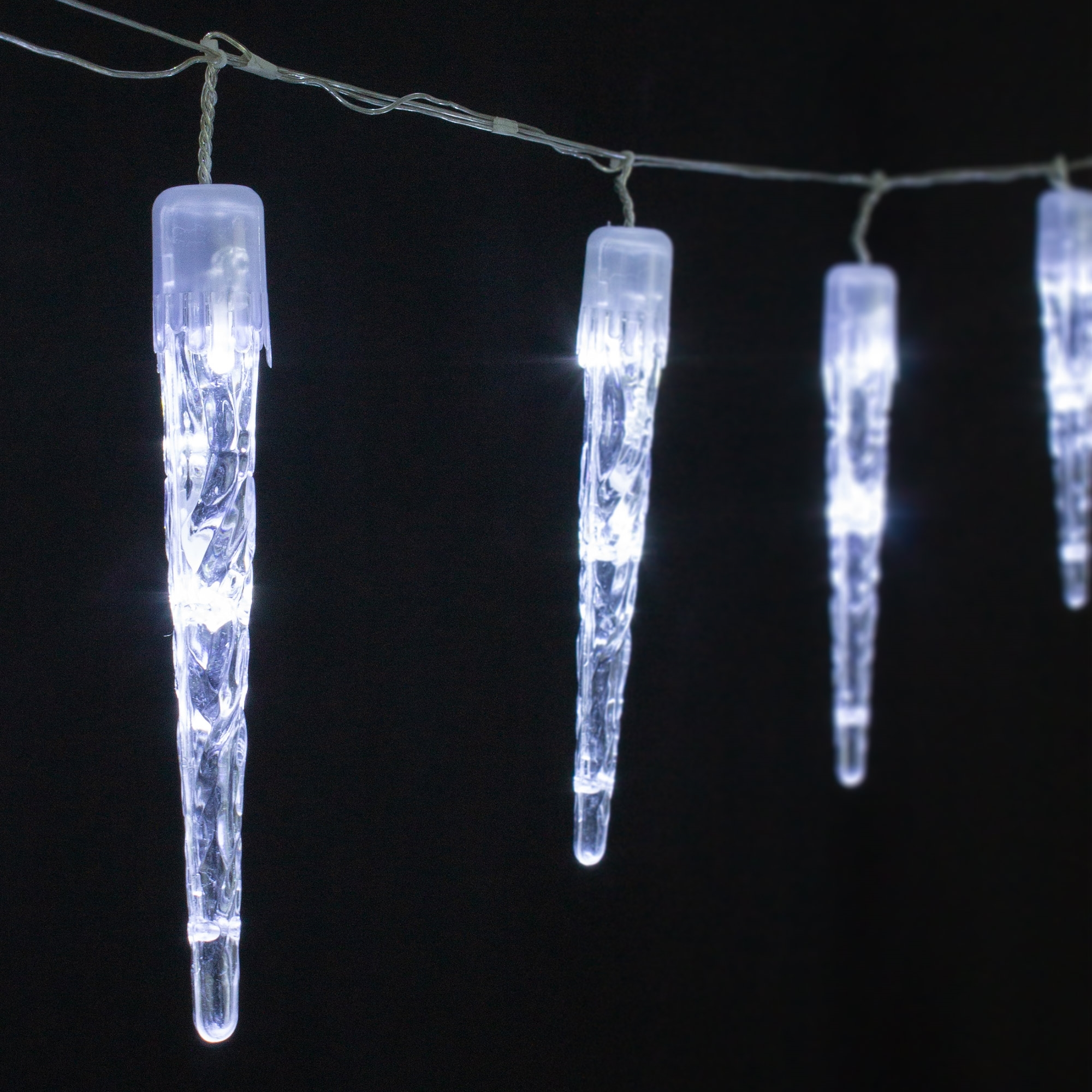 Eiszapfenlichter hängen vor schwarzem Hintergrund. Jeder Eiszapfen ist klar mit einem weißen Licht im Inneren, verbunden mit einem Draht.