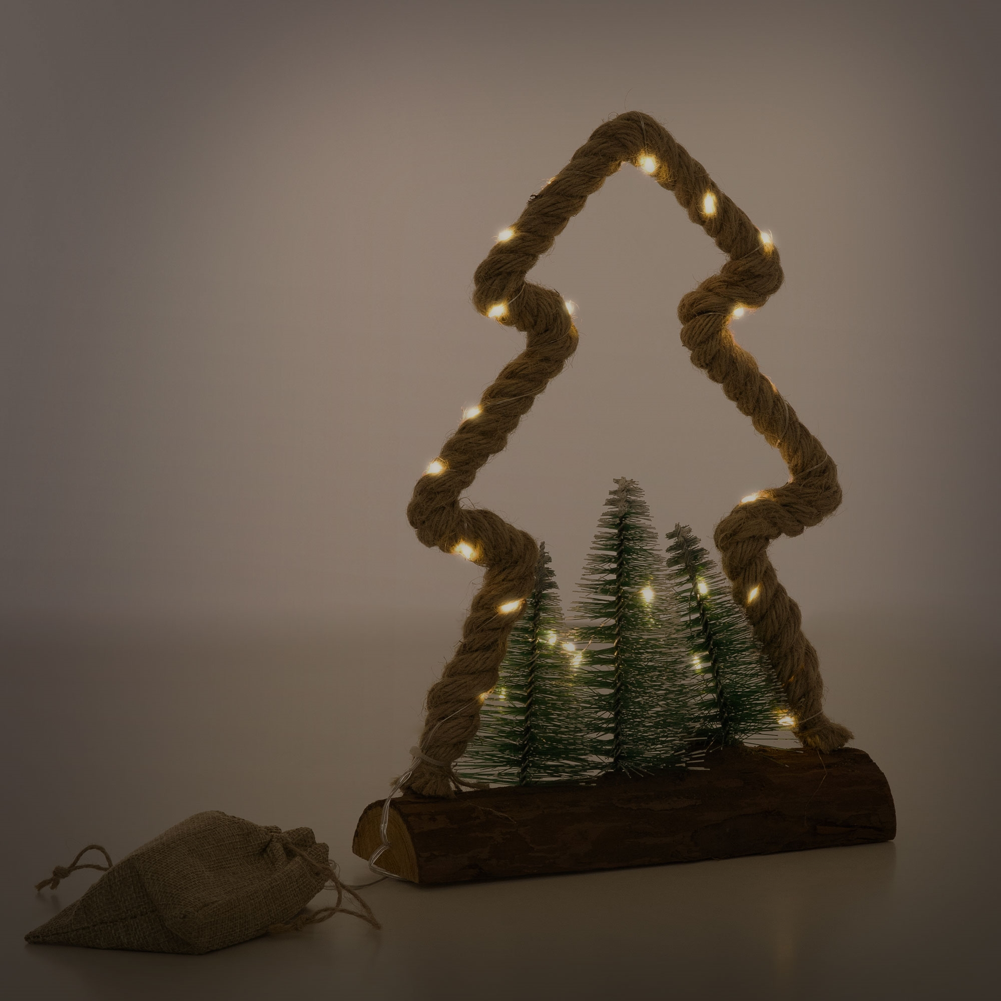 Ein dekorativer Weihnachtsbaum aus Seil und Lichterketten, mit kleinen Bäumen darin. Ein Jutesack befindet sich in der Nähe.