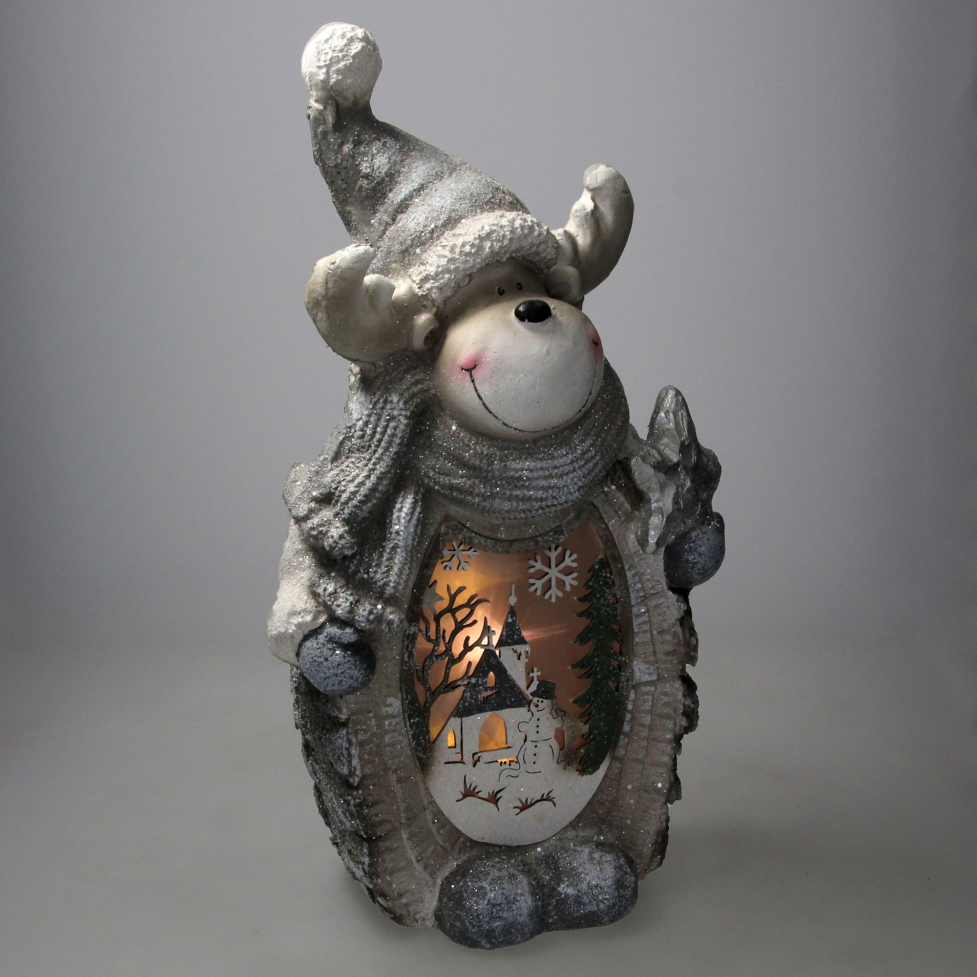 Dekorative Rentierfigur mit Winterszene. Es trägt Hut und Schal und hat ein lächelndes Gesicht.