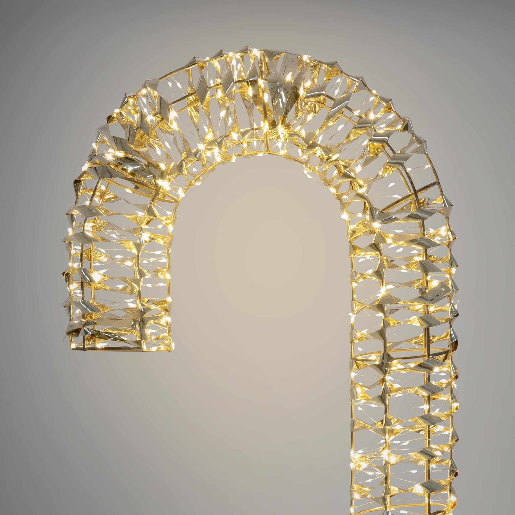 Ein dekorativer Bogen aus goldfarbenen, facettierten Formen mit kleinen, warmweißen Lichtern.