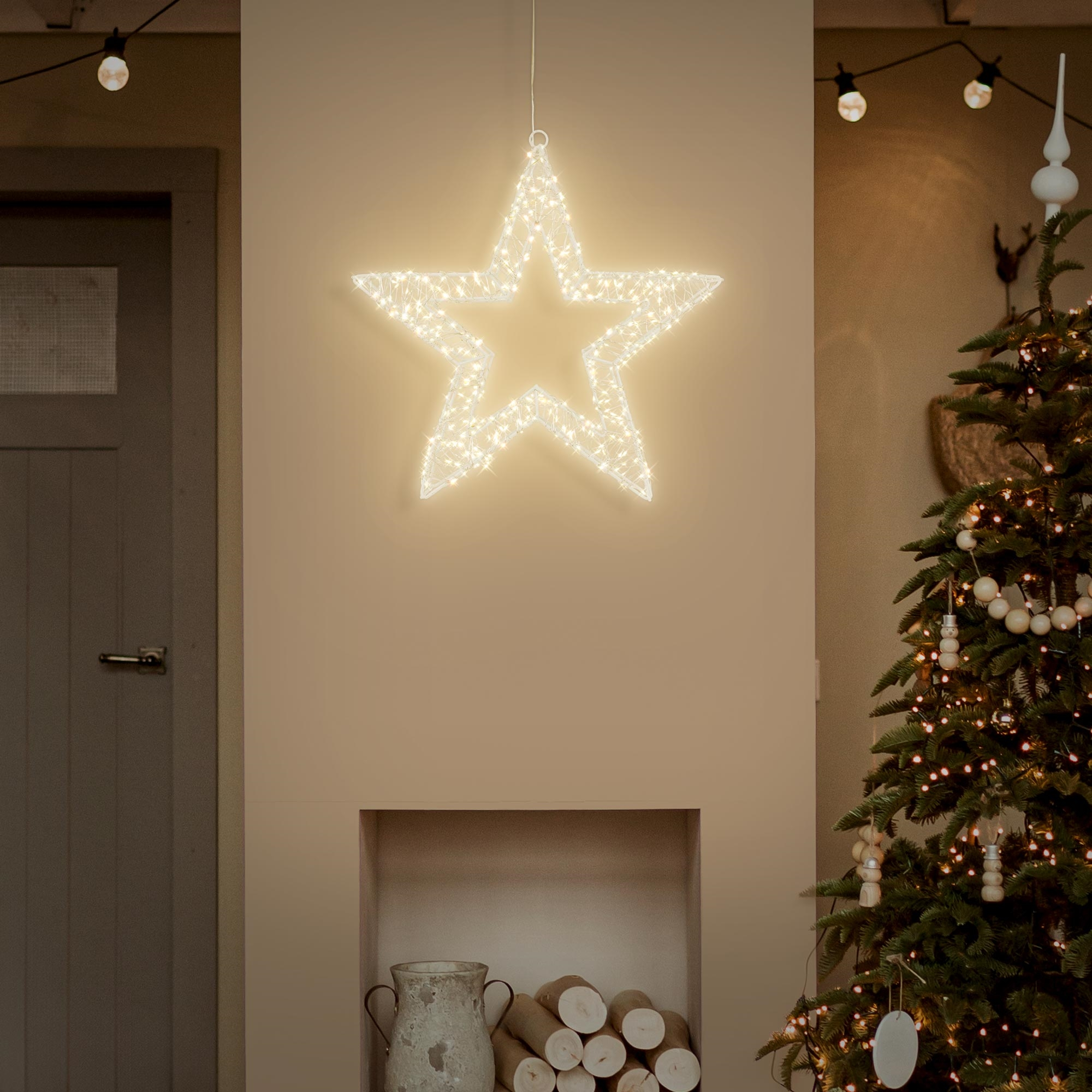 Eine leuchtende Stern-Dekoration hängt über einem Kamin. Rechts steht ein Weihnachtsbaum.