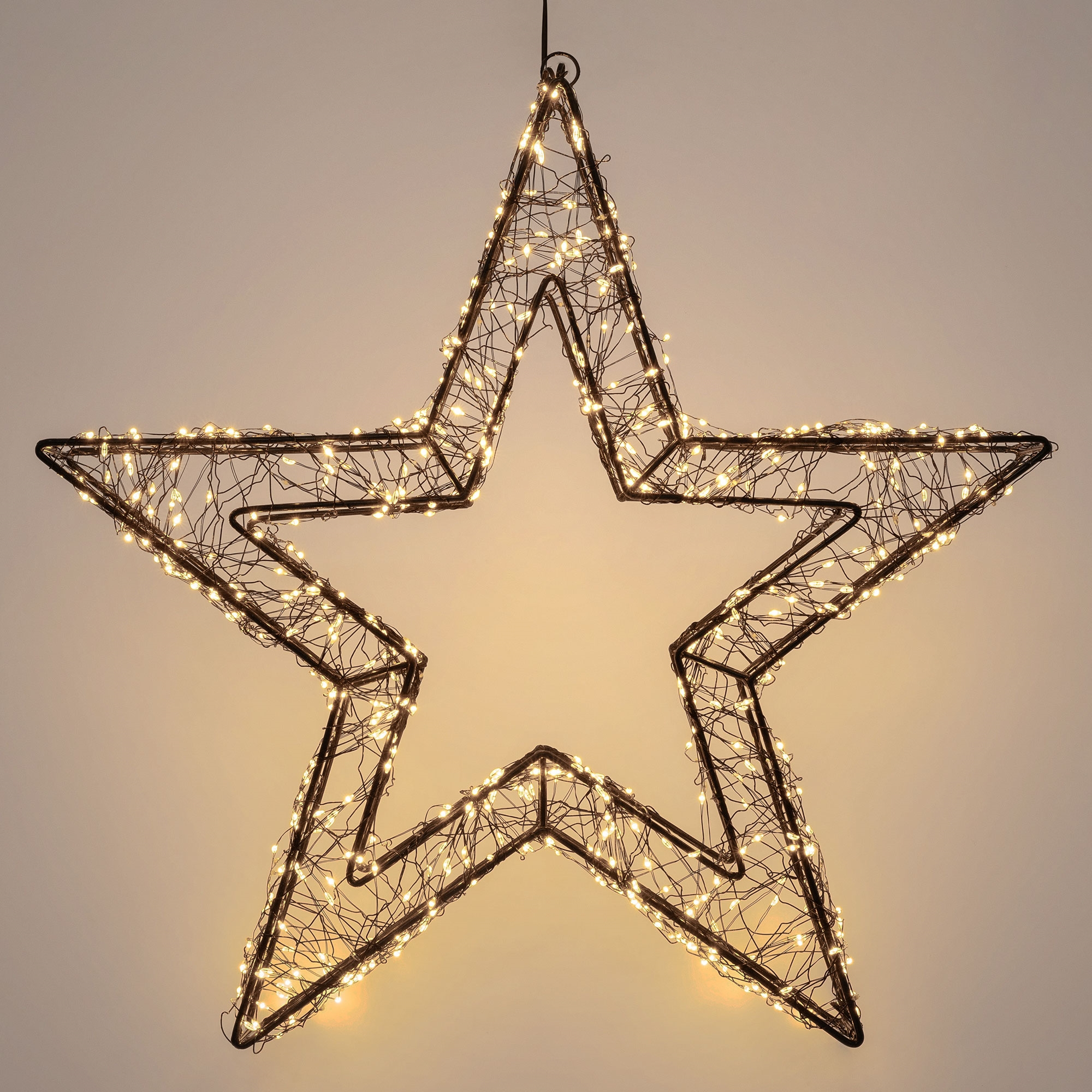 Ein sternförmiger Weihnachtsschmuck mit Lichtern. Er besteht aus schwarzem Draht mit kleinen weißen Lichtern. Der Hintergrund ist cremefarben.
