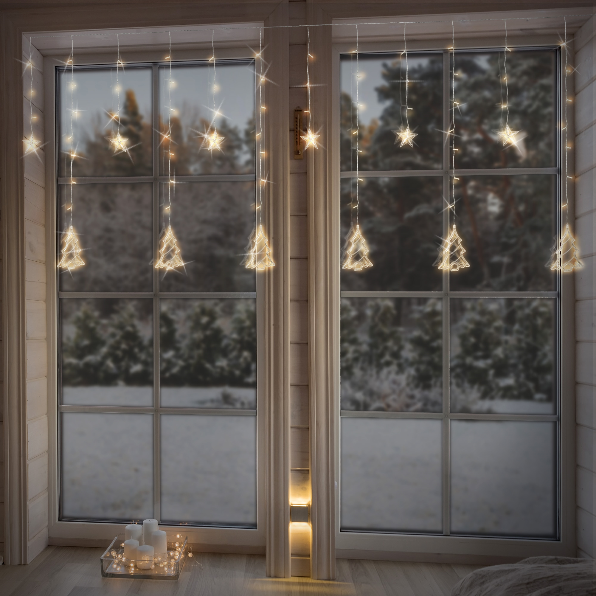 Fenster mit Stern- und Baumlichtern, Schnee draußen. Kerzen in einer Schale auf dem Boden. Winterliche, gemütliche Szene.
