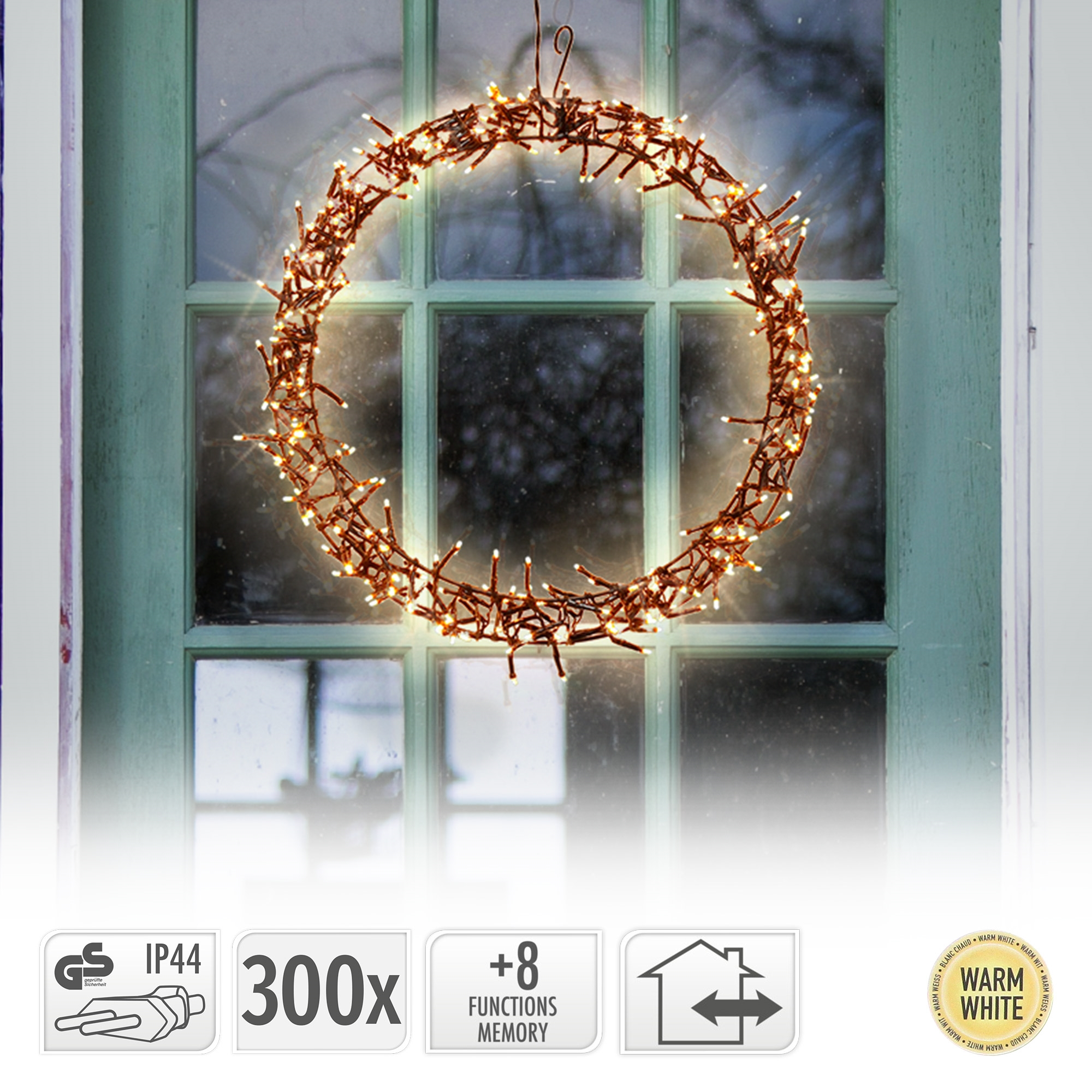 Ein beleuchteter Weihnachtskranz hängt an einem Fenster. Der Kranz ist braun, mit warmweißen Lichtern. Der Fensterrahmen ist grün.