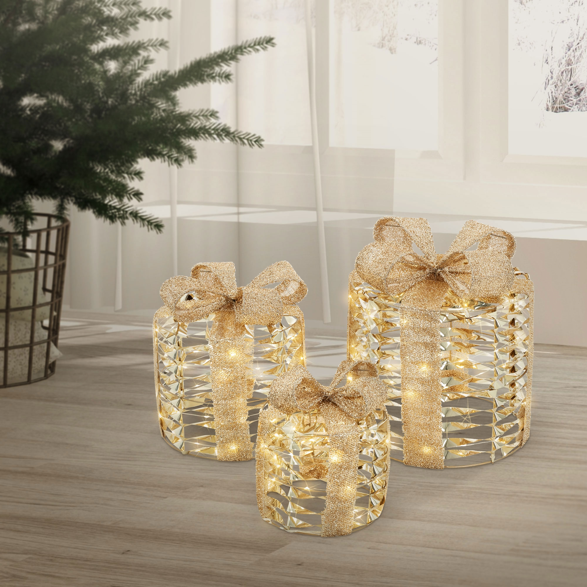 Drei beleuchtete Geschenkboxen mit goldenen Schleifen stehen auf einem Holzboden in der Nähe eines Weihnachtsbaums und eines Fensters.
