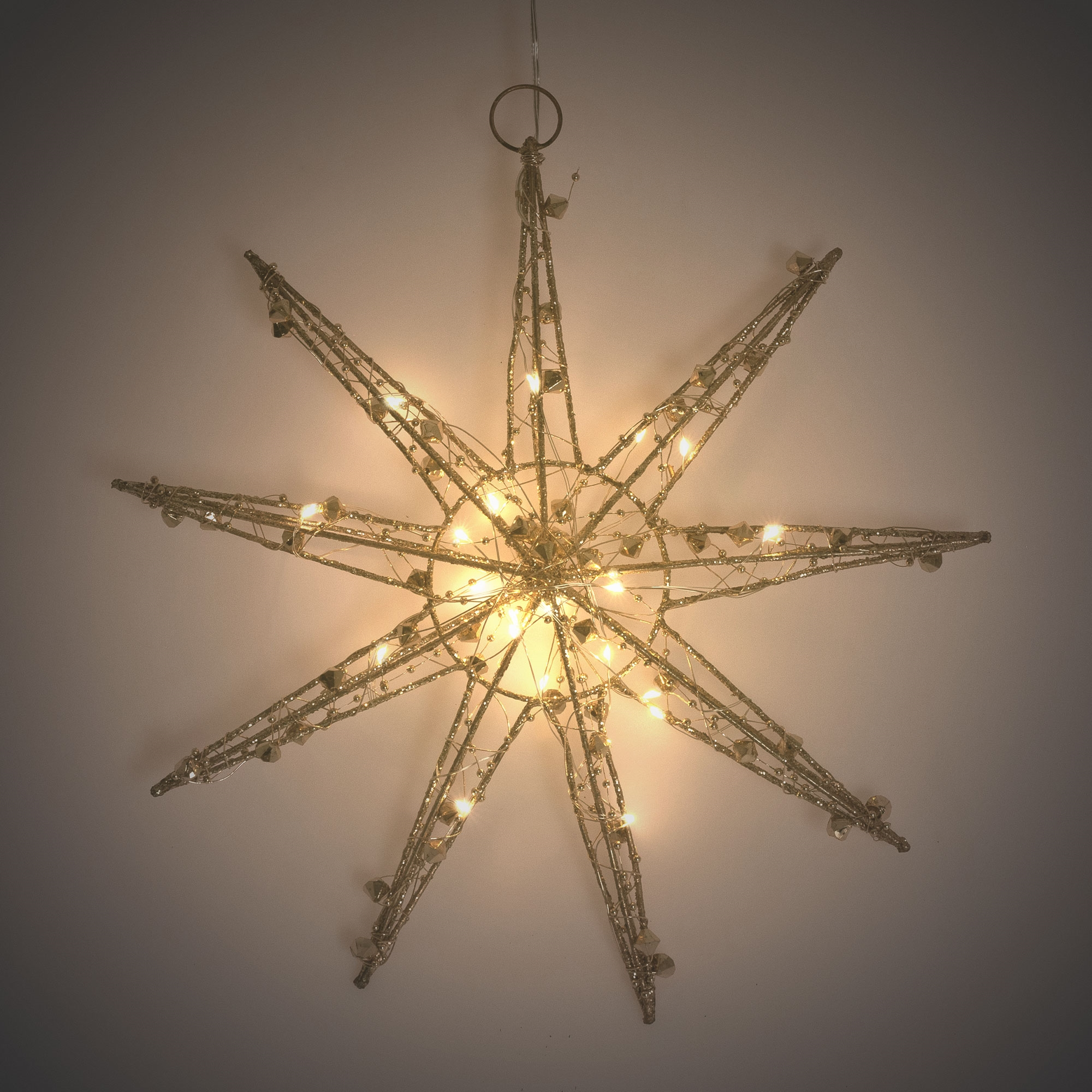Sternförmige Weihnachtsdekoration mit Lichtern und Glitzer, hängt vor weißem Hintergrund.