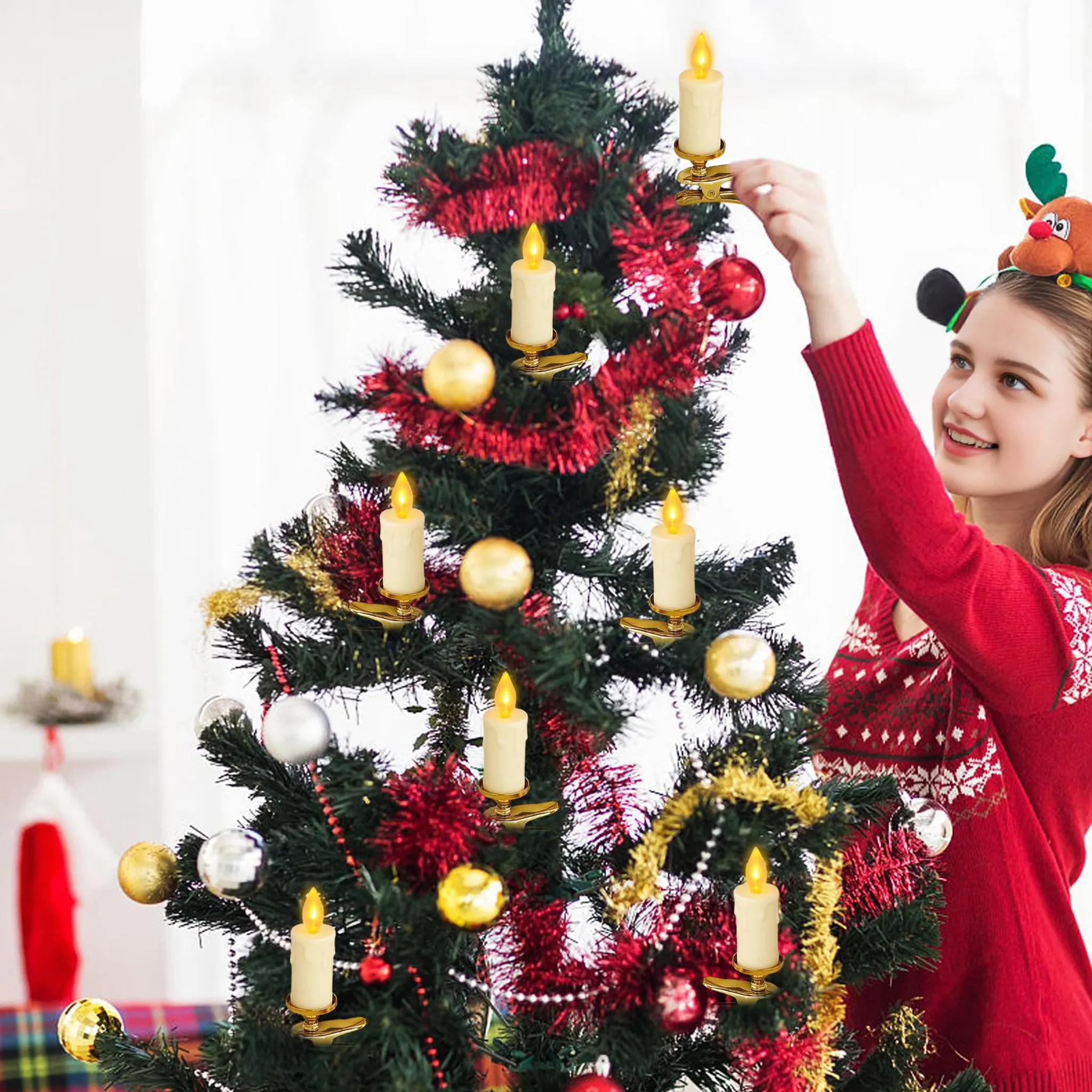 Eine Frau schmückt einen Weihnachtsbaum mit Kerzenlichtern. Sie trägt einen roten Pullover und ein Rentier-Stirnband.