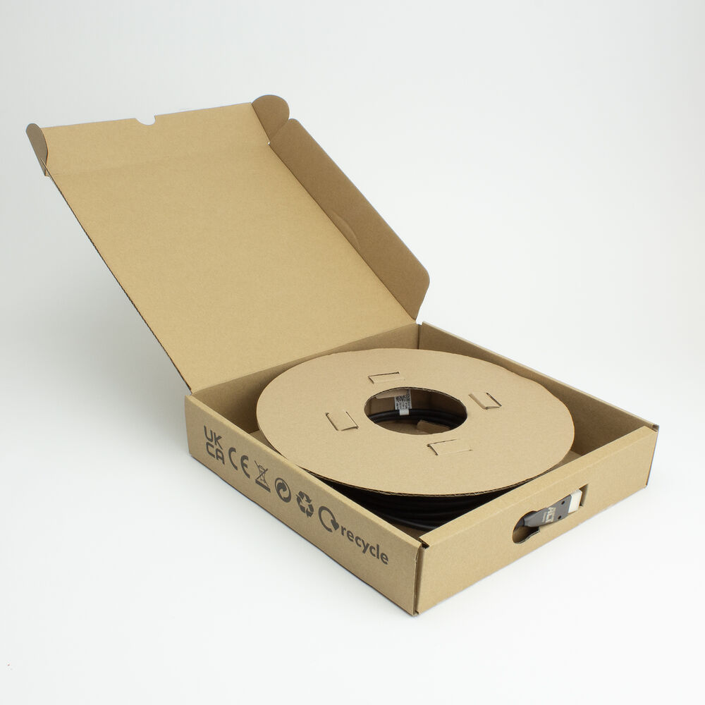 Een open kartonnen doos bevat een grote rol zwarte kabel. De doos heeft recycling- en CE-logo's aan de zijkant.
