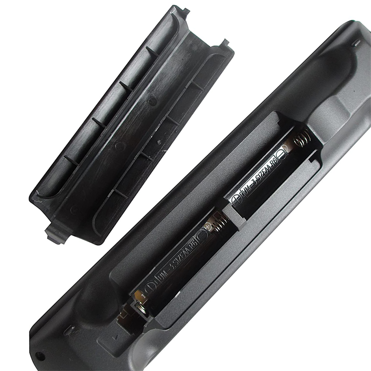 Eine schwarze TV-Fernbedienung mit geöffnetem Batteriefach, das zwei AAA-Batterien zeigt. Der Deckel ist abgenommen.
