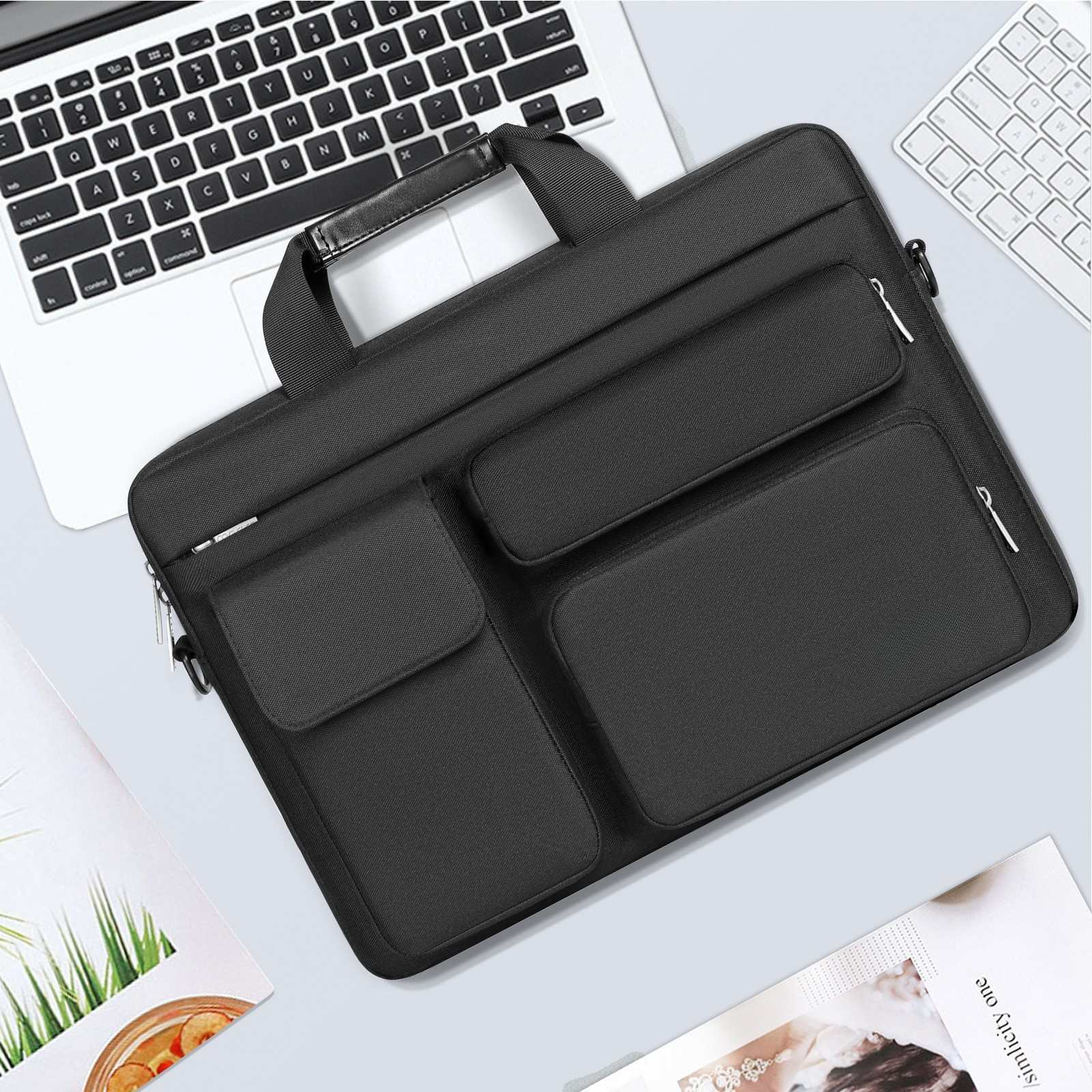 Schwarze Laptoptasche auf einem Tisch mit Laptop und Tastatur. Eine Zeitschrift ist im Vordergrund.