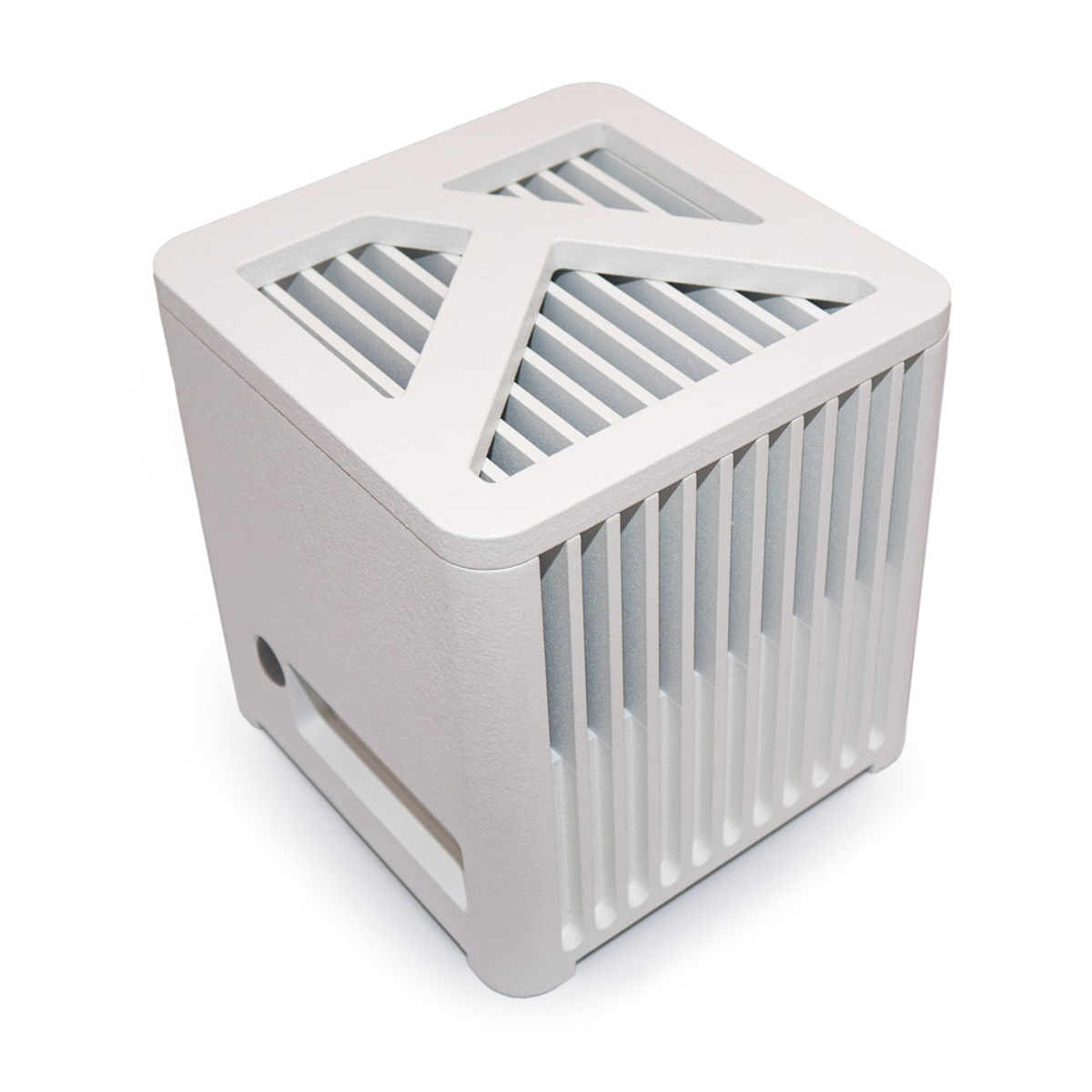 Białe urządzenie w kształcie kostki z żłobionym wierzchem i bokami. Posiada trójkątny wzór na górze i prostokątny otwór z boku.