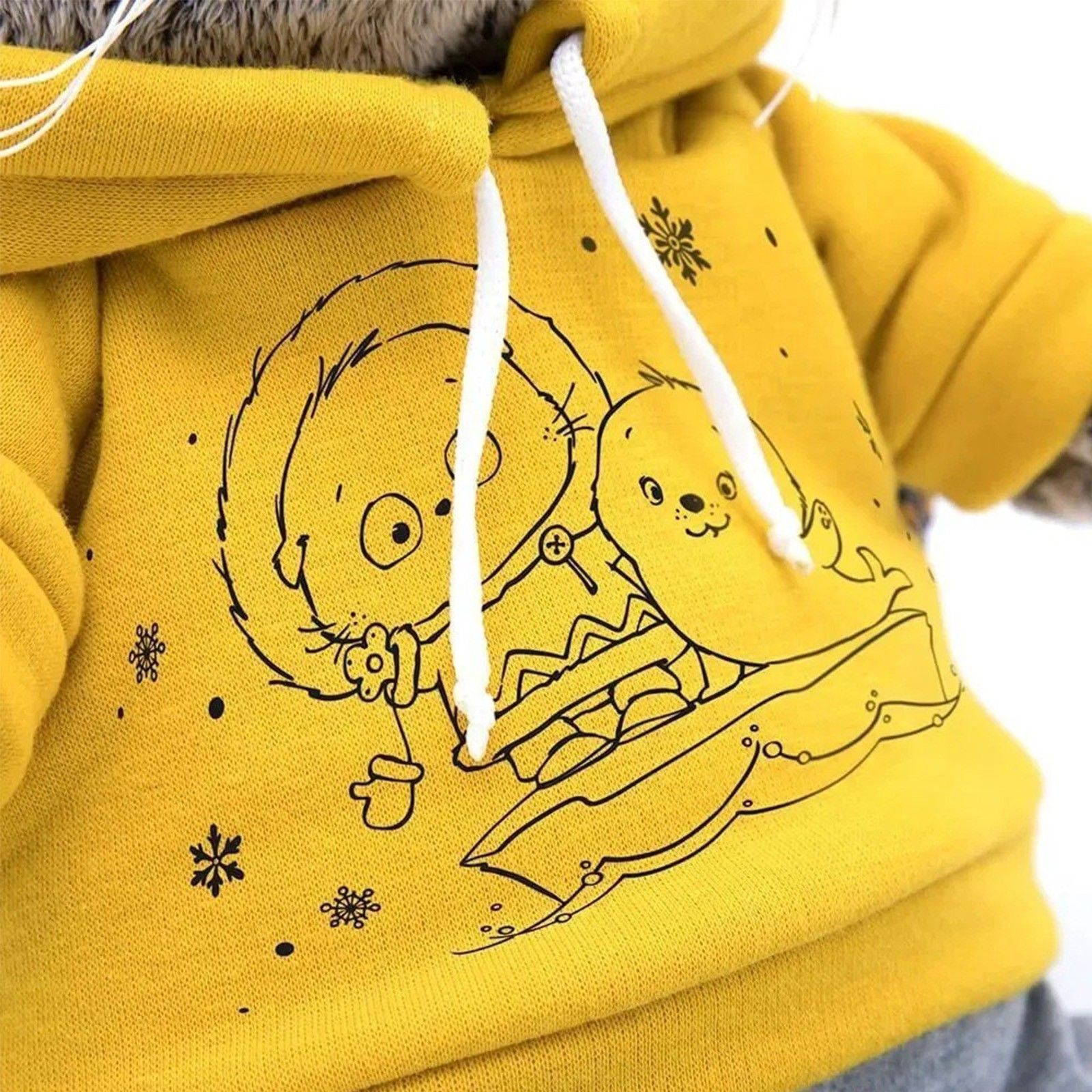 Gelber Kapuzenpullover mit Cartoon-Robbe und -Bär. Schwarze Linienkunst. Weiße Kordelzüge und Schneeflocken. Graues Fell oben.