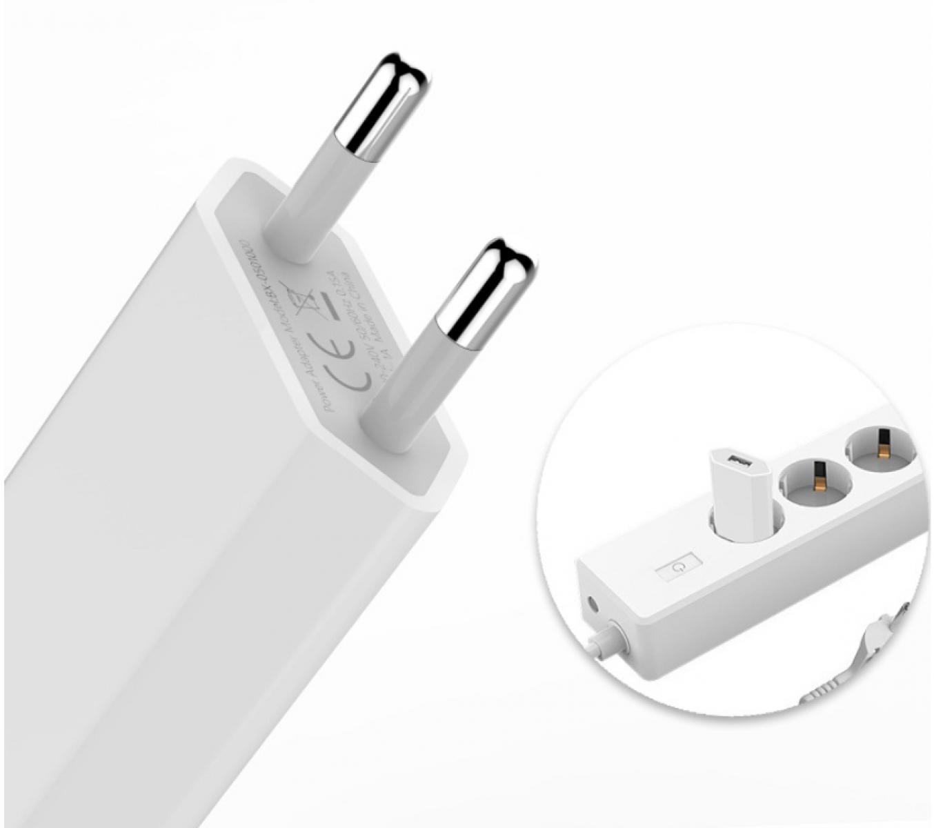 Ein weißer Netzadapter mit zwei silbernen Stiften und eine Nahaufnahme einer Steckdosenleiste mit USB-Ladegerät.