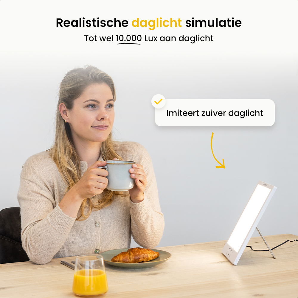 A woman sits at a table, holding a mug. There's a croissant, juice, and a light therapy lamp. Text reads 'daylight simulation'.