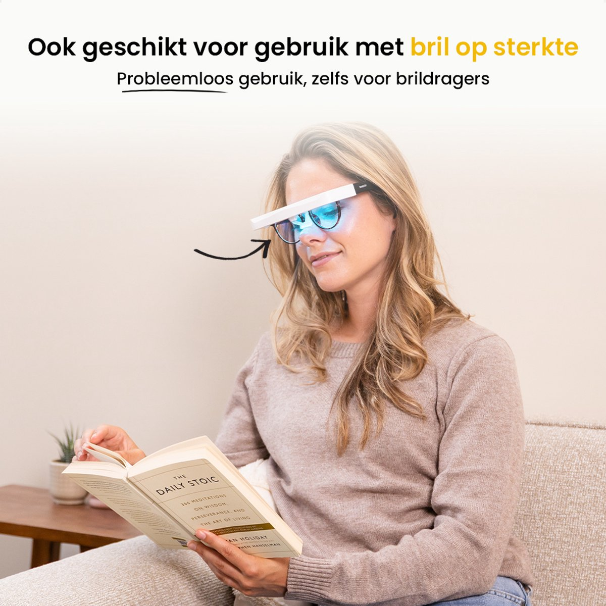 Woman wearing glasses with a white visor, reading a book titled 'The Daily Stoic' while sitting on a couch.