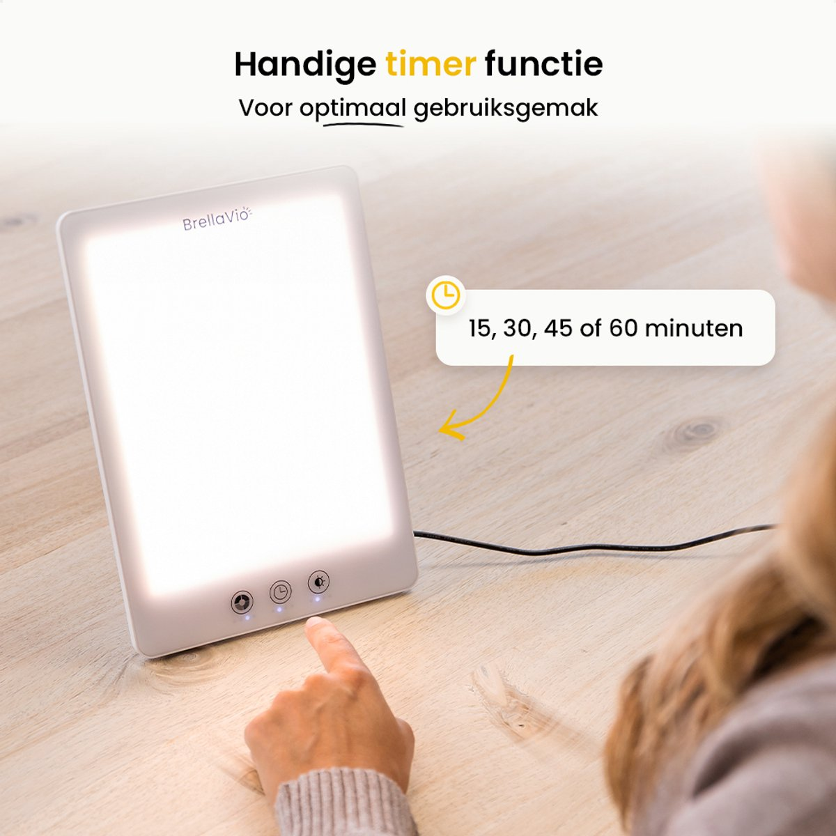 A person's finger is pressing a button on a white light therapy lamp. The lamp is on a wooden surface. Text shows timer options.