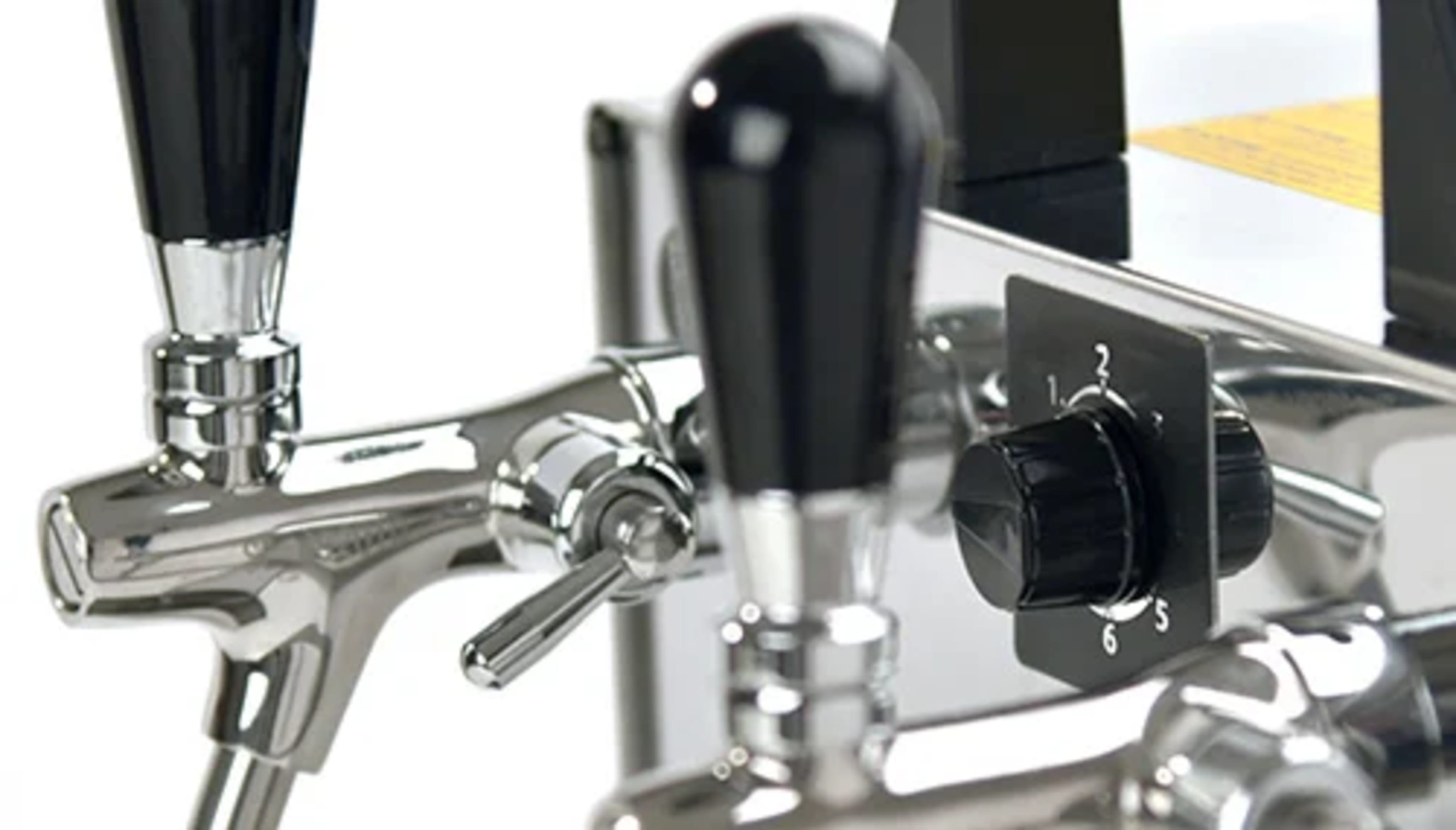 Primo piano di un sistema di spillatura birra cromato con maniglie nere e un quadrante di controllo, con i numeri 1-6.