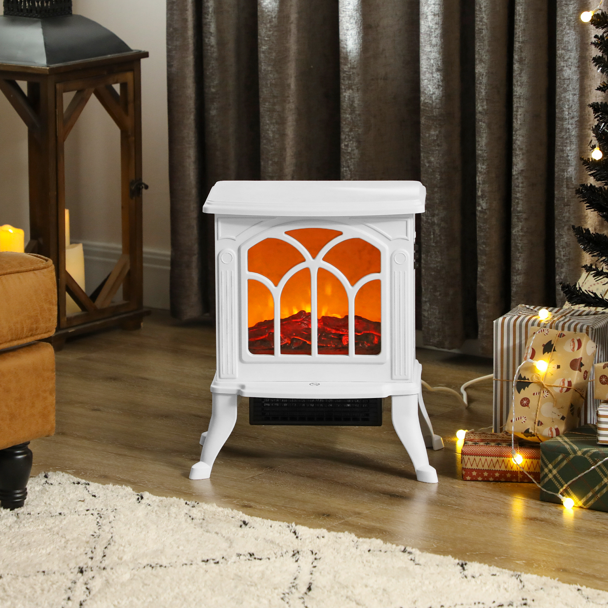 Una chimenea eléctrica blanca con efecto de llama, colocada en una habitación decorada para Navidad, con regalos y un árbol.