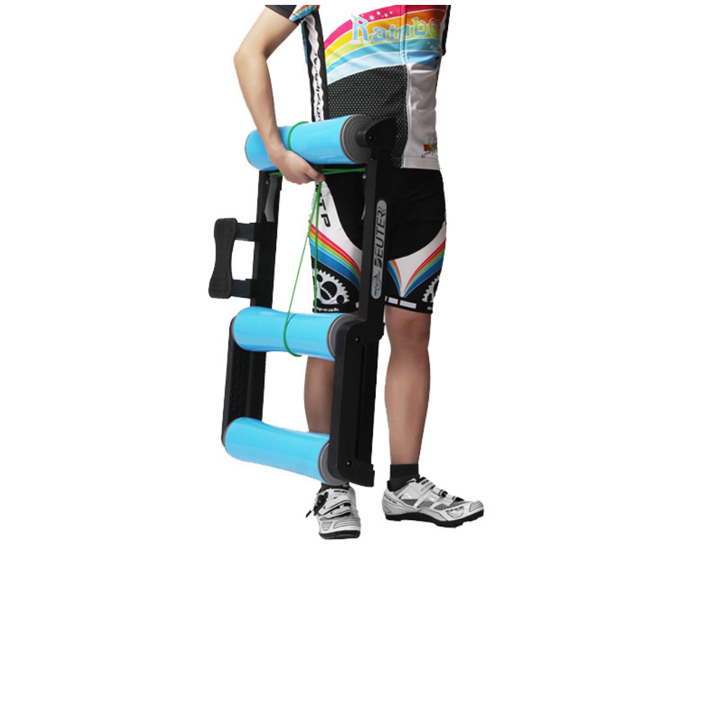 Una persona sostiene un rodillo de ejercicio negro y azul. Lleva un equipo de ciclismo y zapatos. El rodillo tiene tres cilindros azules.